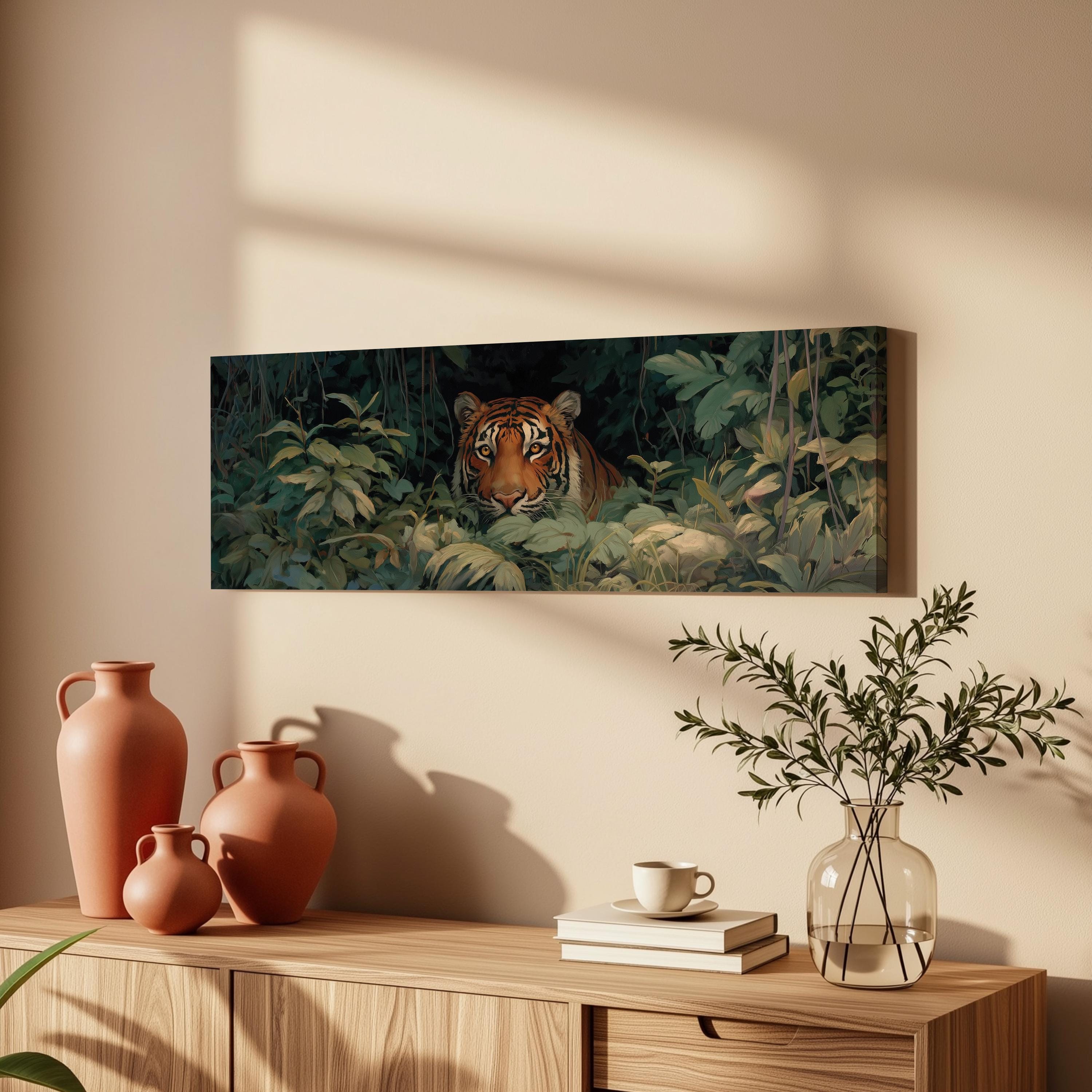 a wooden cabinet with a vase, a stack of books, and a plant on top. Above the cabinet, there is a painting of a tiger peeking out from the foliage.