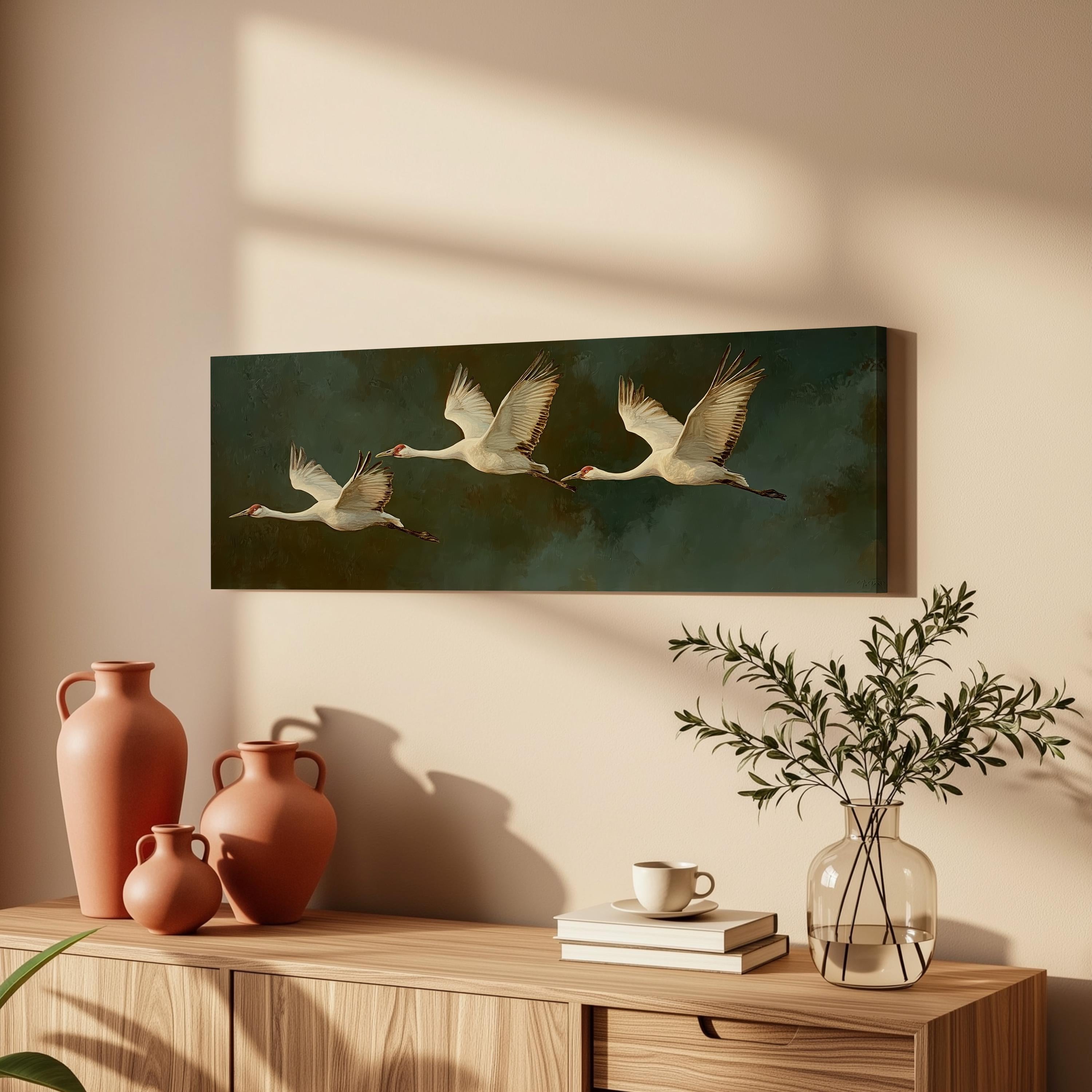 a wooden cabinet with a painting of three white birds in flight, a vase with greenery, and a stack of books on top.
