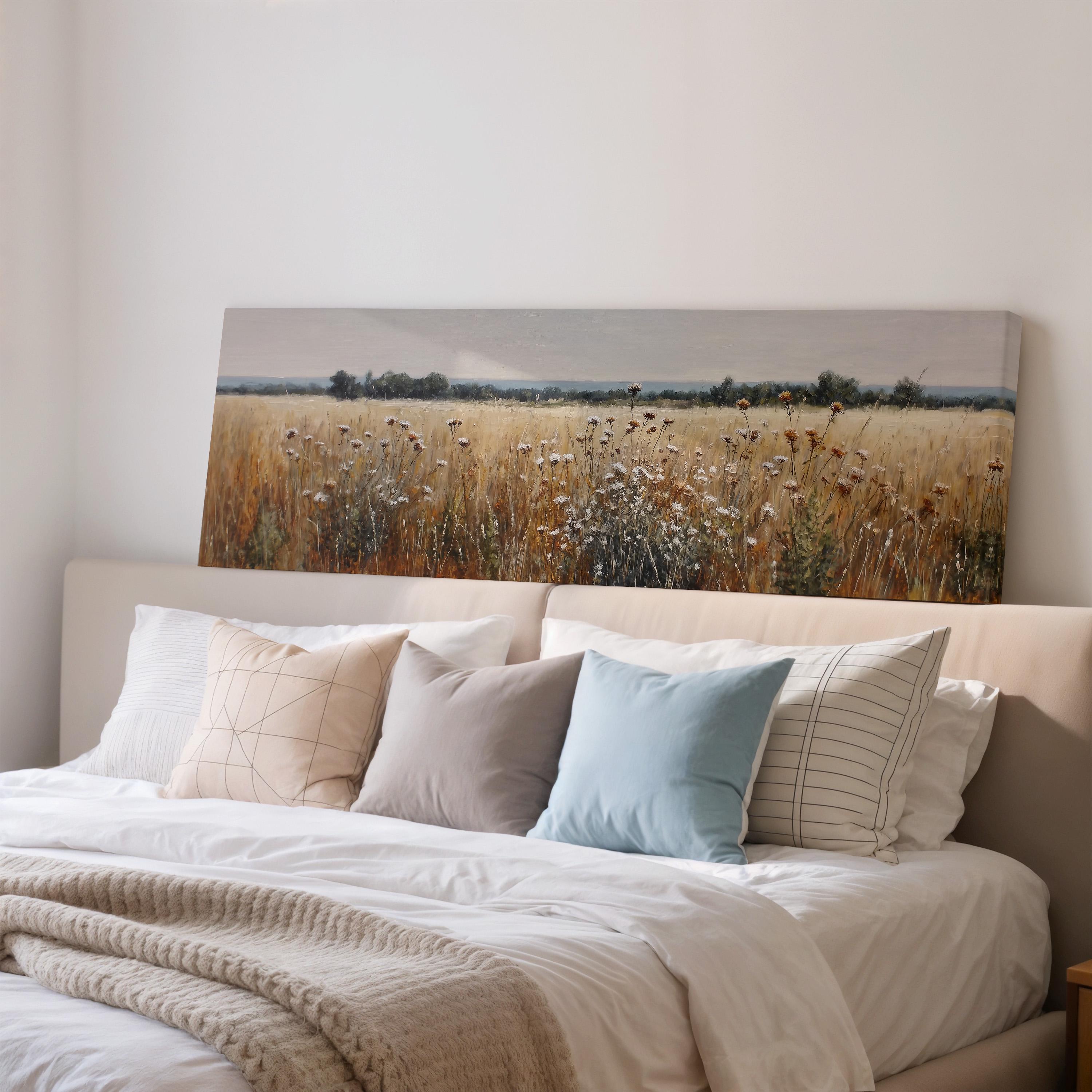 a large bed with a white comforter and pillows, and a painting of a field of flowers hanging above it.