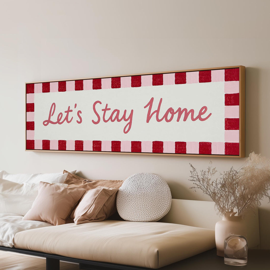 Let's stay home sign with a red checked border long horizontal canvas print above a sofa in a living room