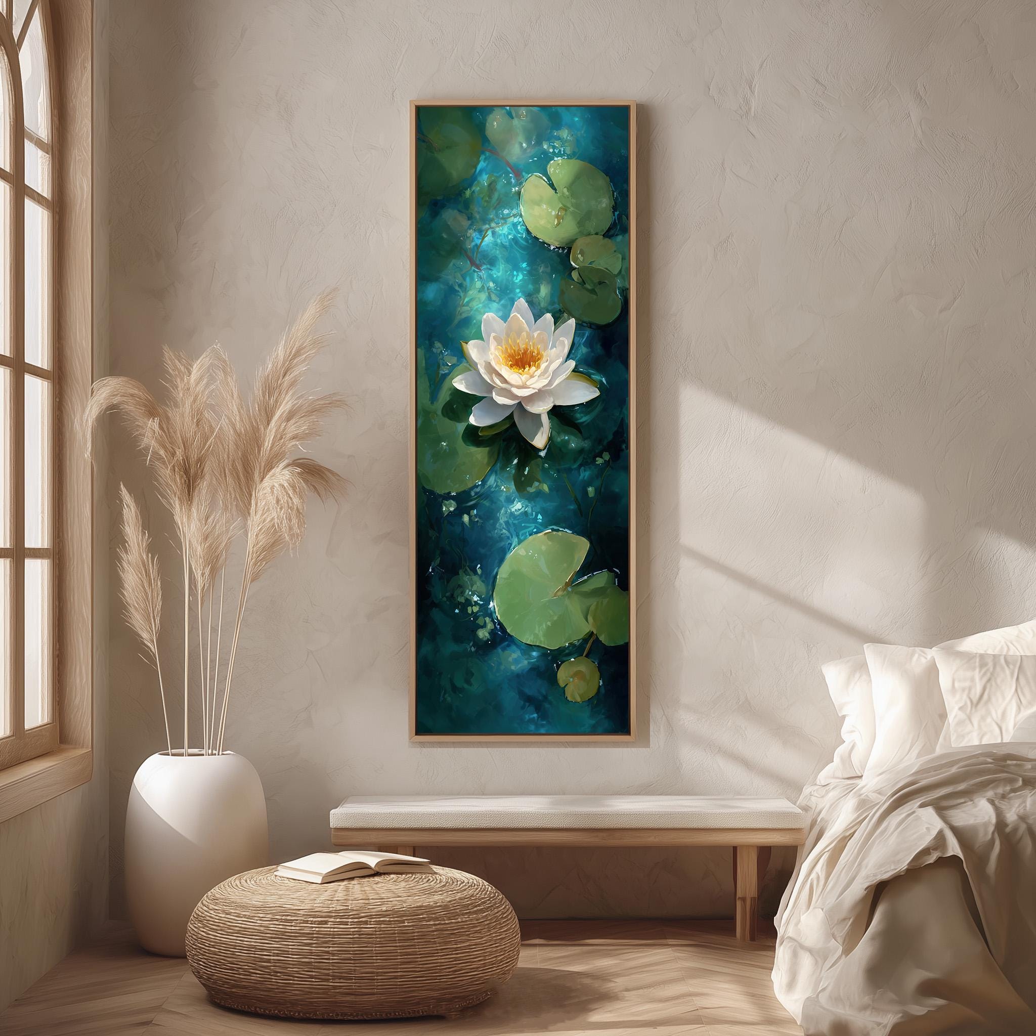 a serene indoor setting with a large painting of a white lotus flower on a blue background hanging on the wall. The painting is framed in a wooden frame and is the focal point of the room. The room is decorated with a white bed, a wicker ottoman, and a potted plant, creating a calm and peaceful atmosphere.