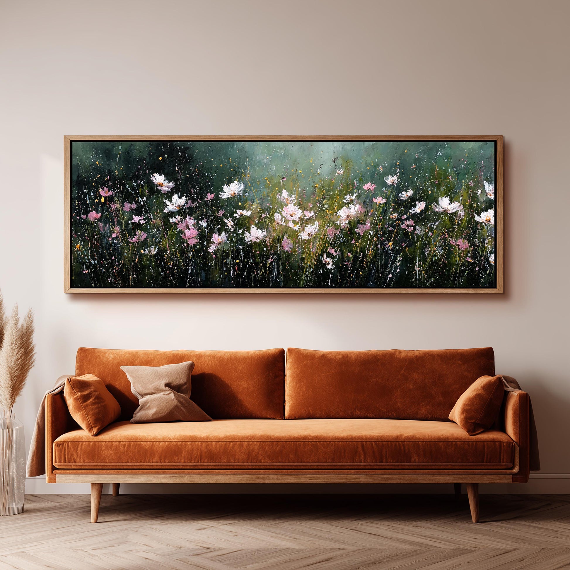 a large, framed painting of a field of flowers hanging on a wall above a brown sofa.