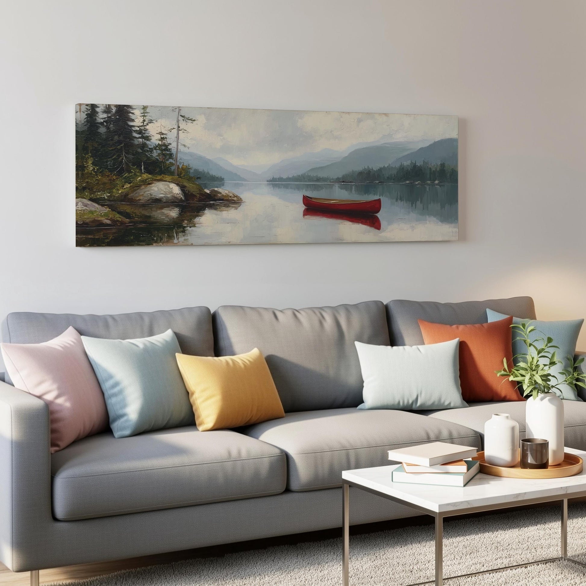 a gray couch with colorful throw pillows, a coffee table, and a painting of a red canoe on a lake hanging on the wall above it.