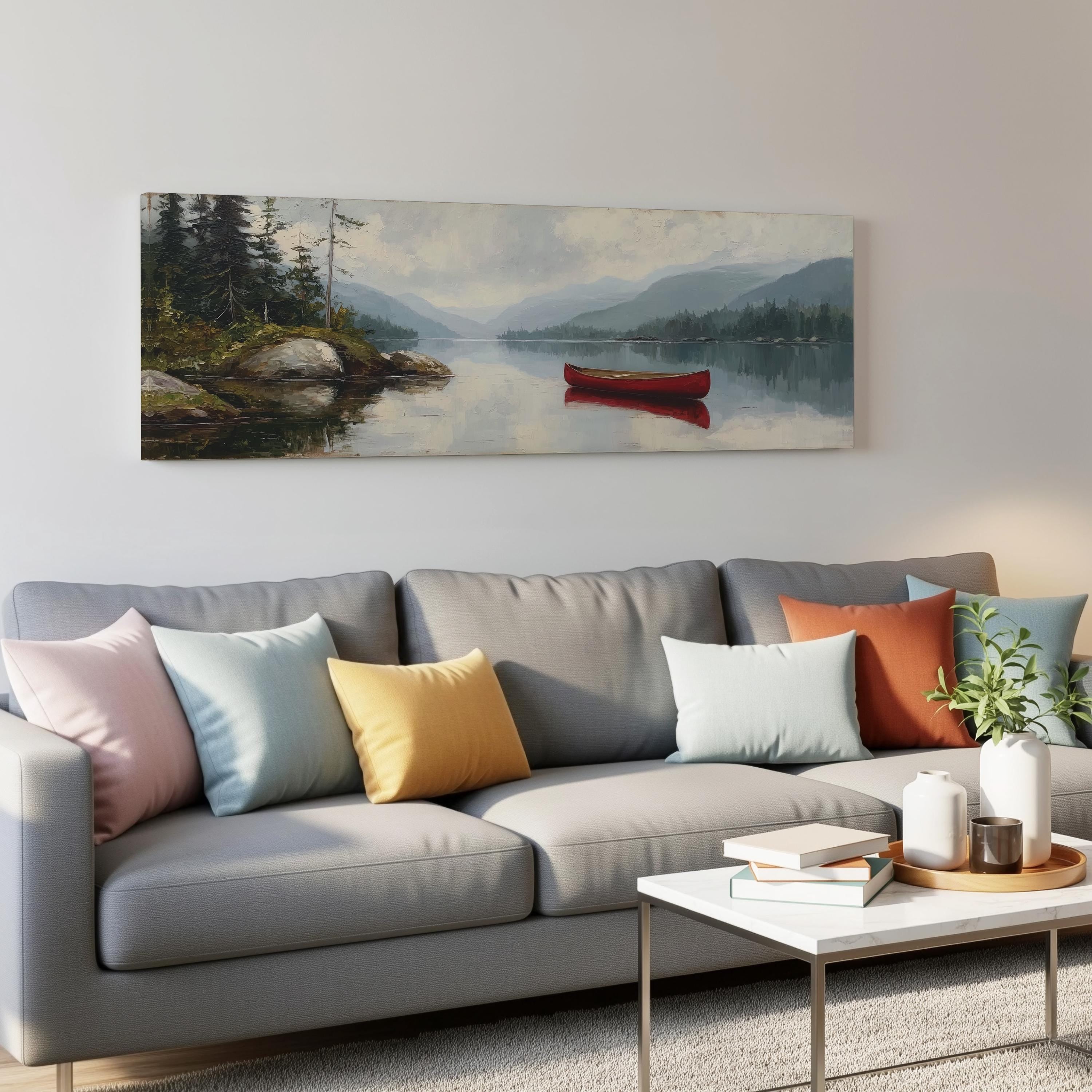 a gray couch with colorful throw pillows, a coffee table, and a painting of a red canoe on a lake hanging on the wall above it.
