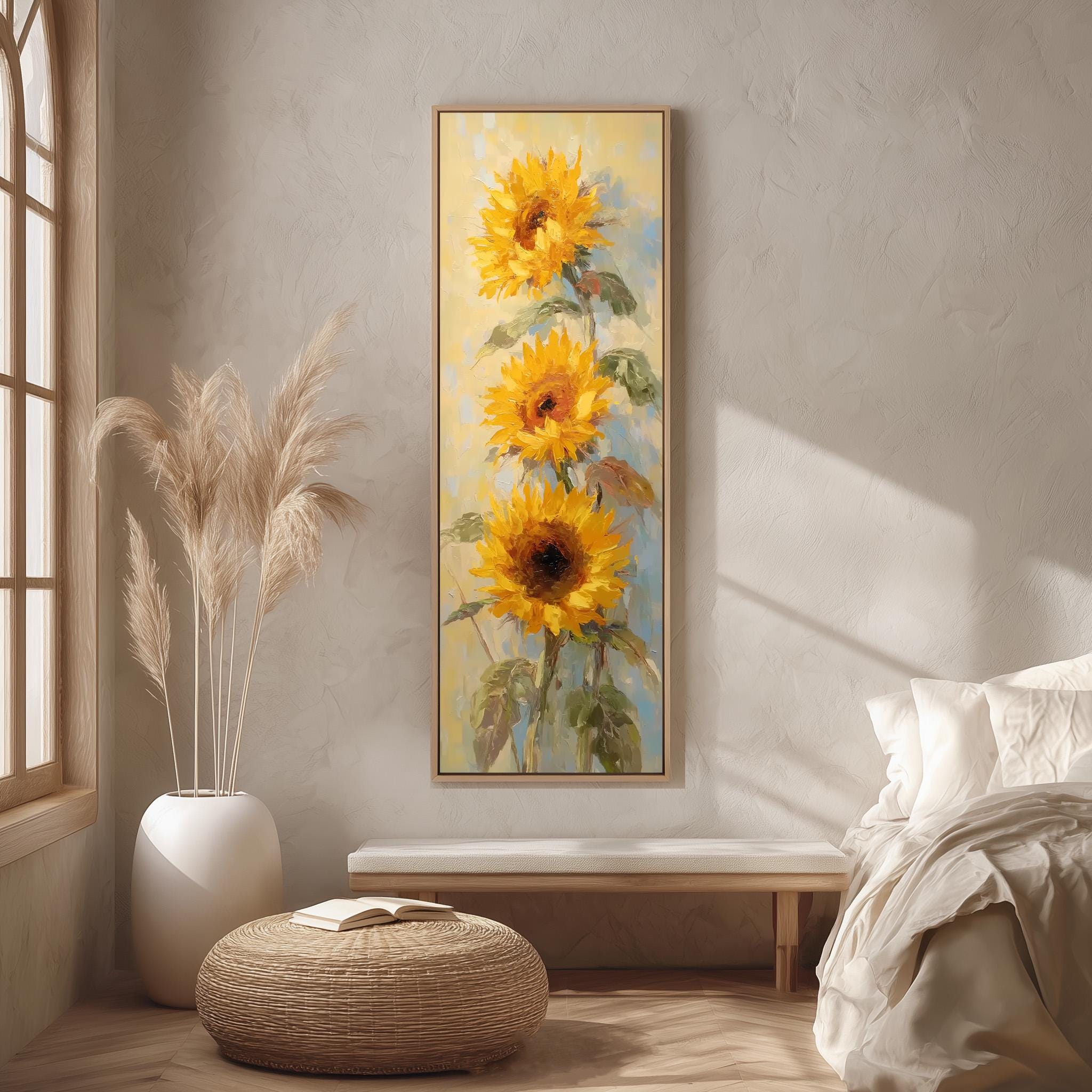 a large painting of three sunflowers hanging on a wall in a room with a bed, a wicker ottoman, and a potted plant.