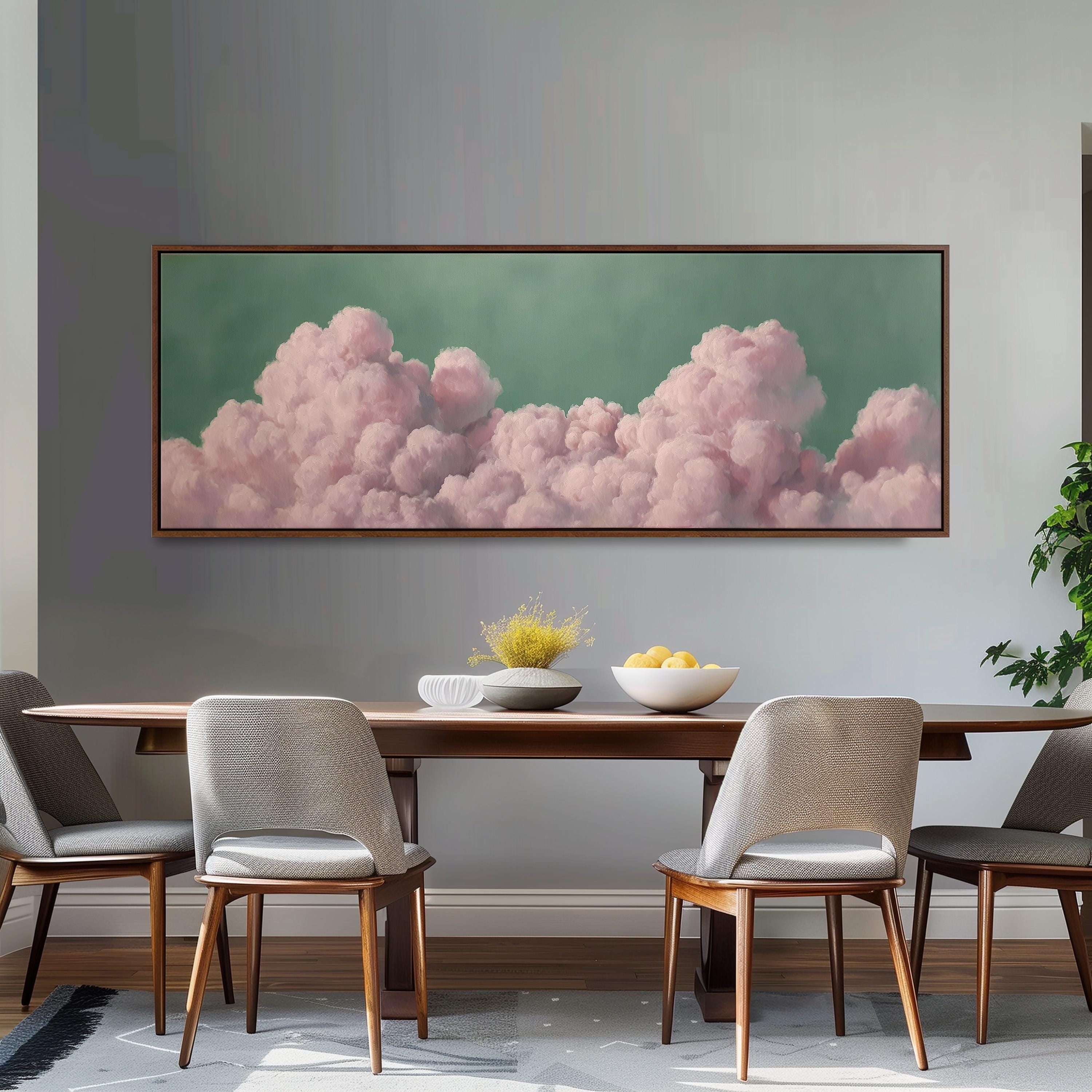 a dining room with a large framed picture of pink clouds hanging on the wall above a wooden dining table with four chairs. The table is set with a bowl of fruit and a vase of flowers, creating a cozy and inviting atmosphere.