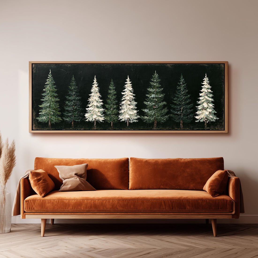 Row of snowy pine trees on black long horizontal canvas print above a sofa in a living room
