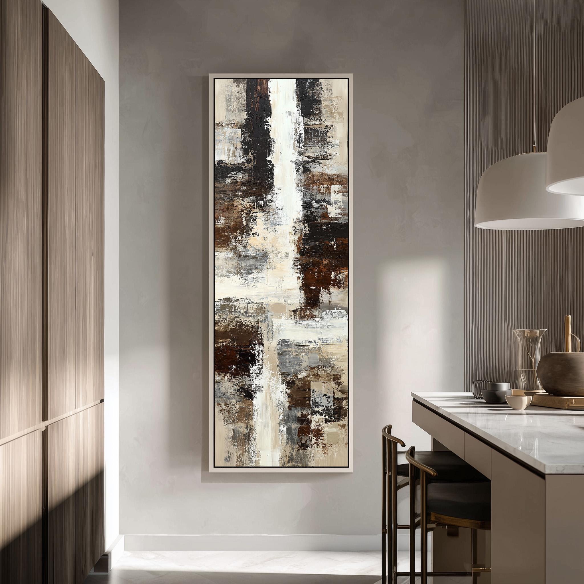 a modern kitchen with a large abstract painting hanging on the wall above a counter. The painting has a mix of brown, white, and gray colors, creating a visually striking contrast. The kitchen is well-lit, with a pendant light hanging above the counter and a wooden cabinet visible in the background.