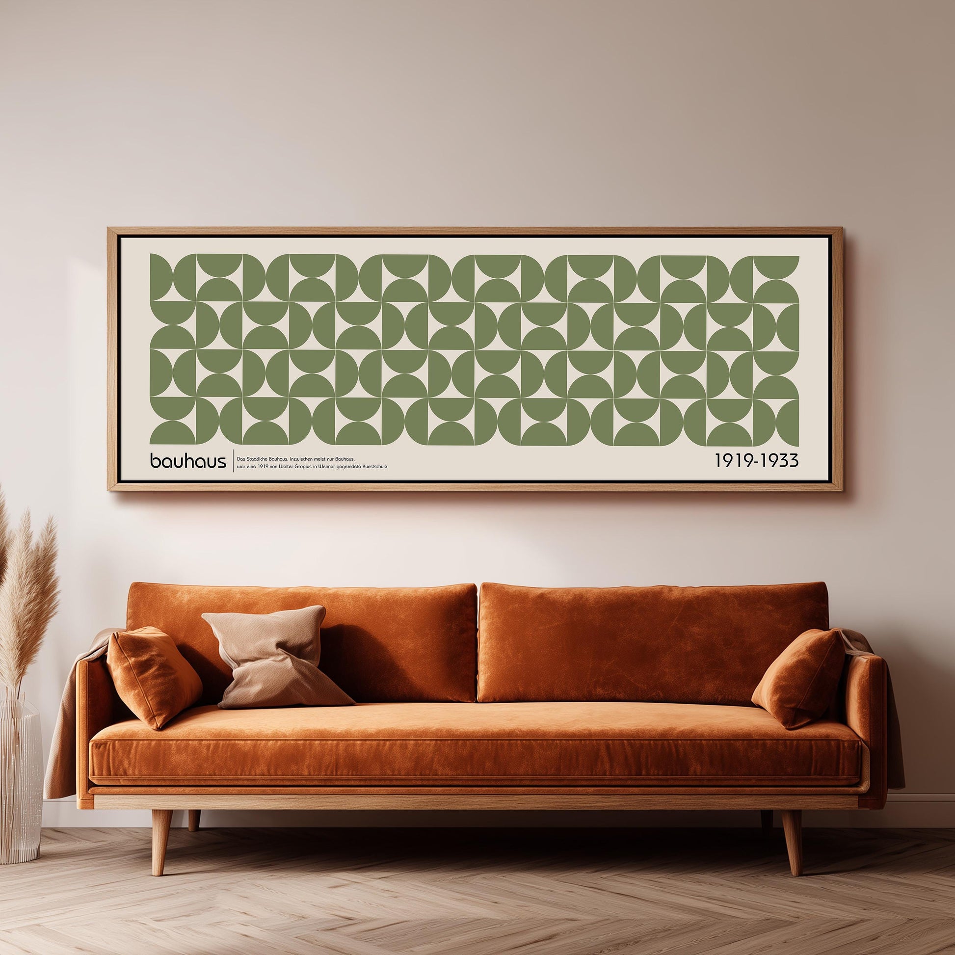 a large framed poster of a repeating geometric pattern in shades of green and white, hanging on a wall above a brown sofa with a wooden frame.