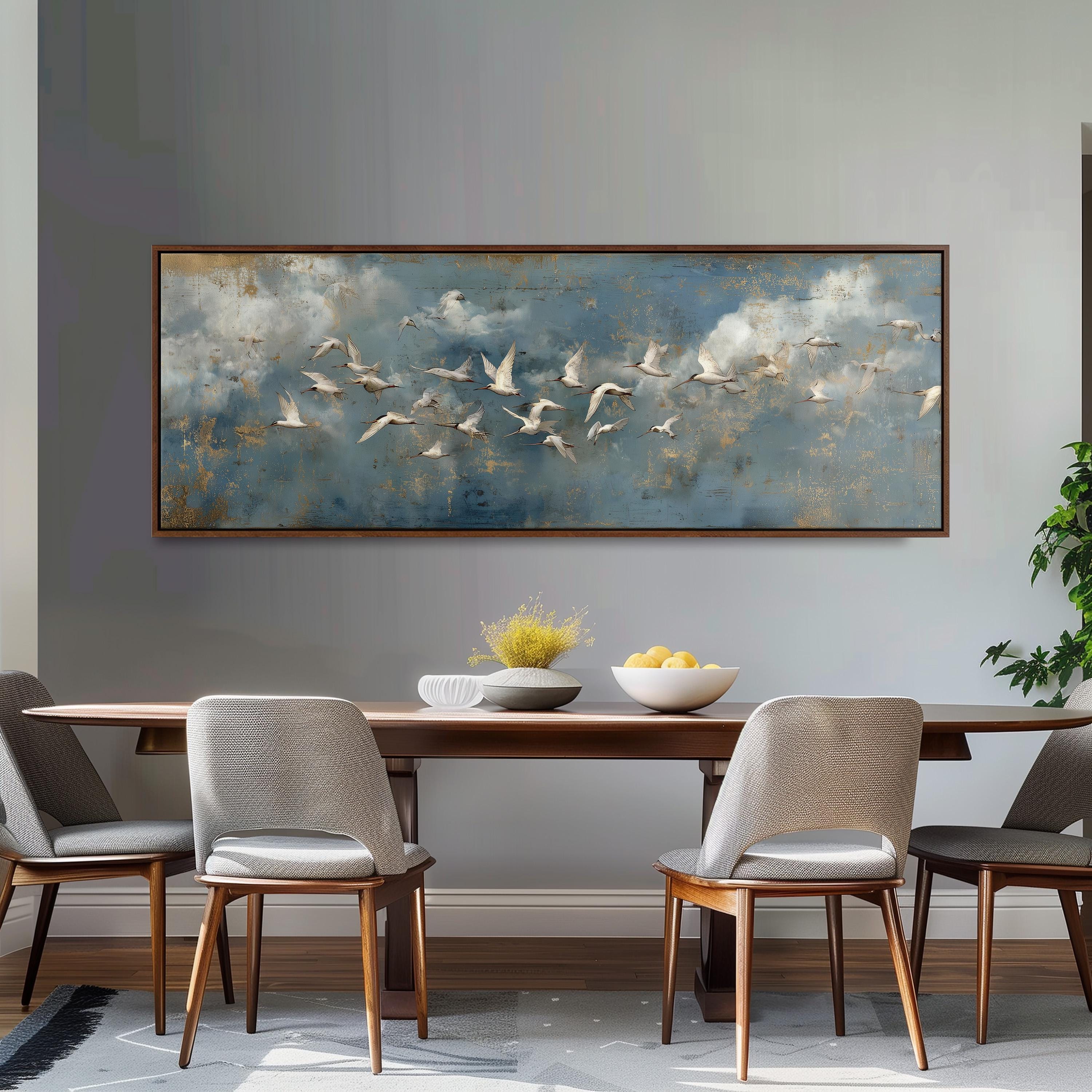 a dining room with a large painting of birds in flight hanging on the wall above a wooden dining table with four chairs. The table is set with a bowl of fruit and a vase of flowers, creating a cozy and inviting atmosphere.