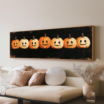 Row of smiling jack-o'-lanterns long horizontal canvas print above a sofa in a living room