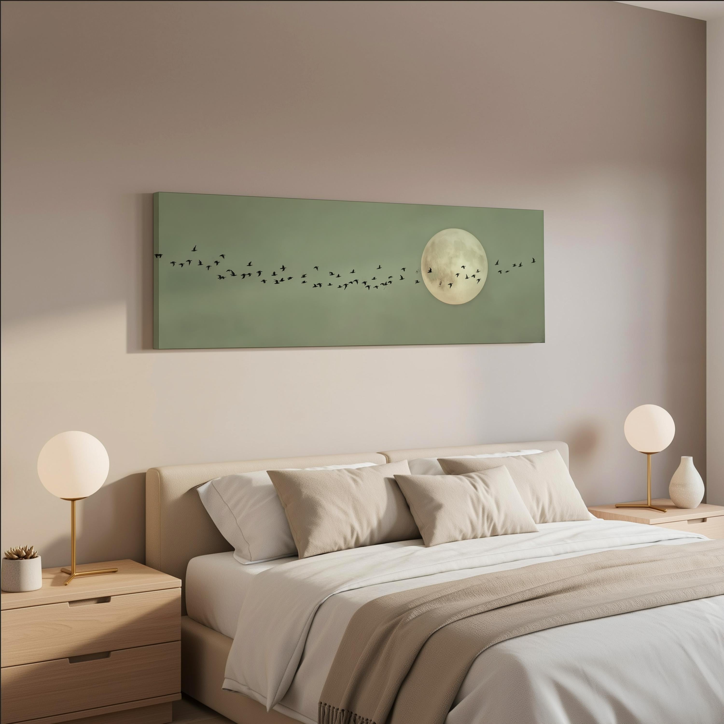 a serene bedroom scene with a large bed adorned with white linens and beige pillows. Above the bed, a large green canvas features a depiction of a full moon and a flock of birds. Two white lamps flank the bed, and the walls are painted in a light beige color.