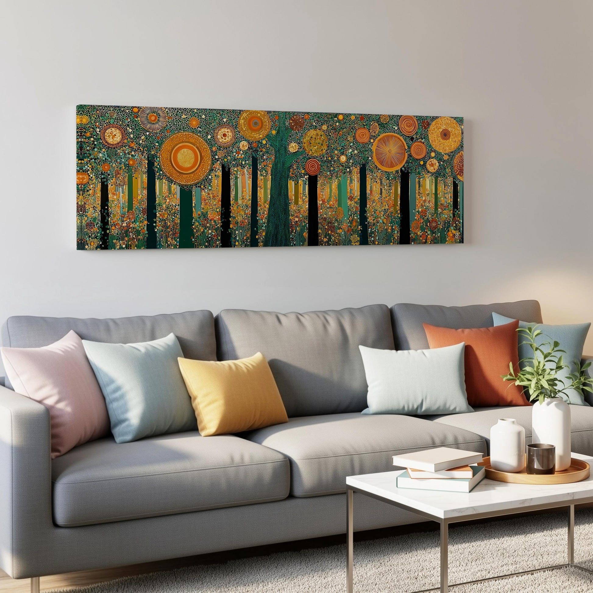 a modern living room with a gray sofa adorned with colorful throw pillows. Above the sofa, a large abstract painting of a forest with vibrant orange and yellow flowers is displayed on the wall. The room also includes a coffee table with books and a plant, creating a cozy and inviting atmosphere.