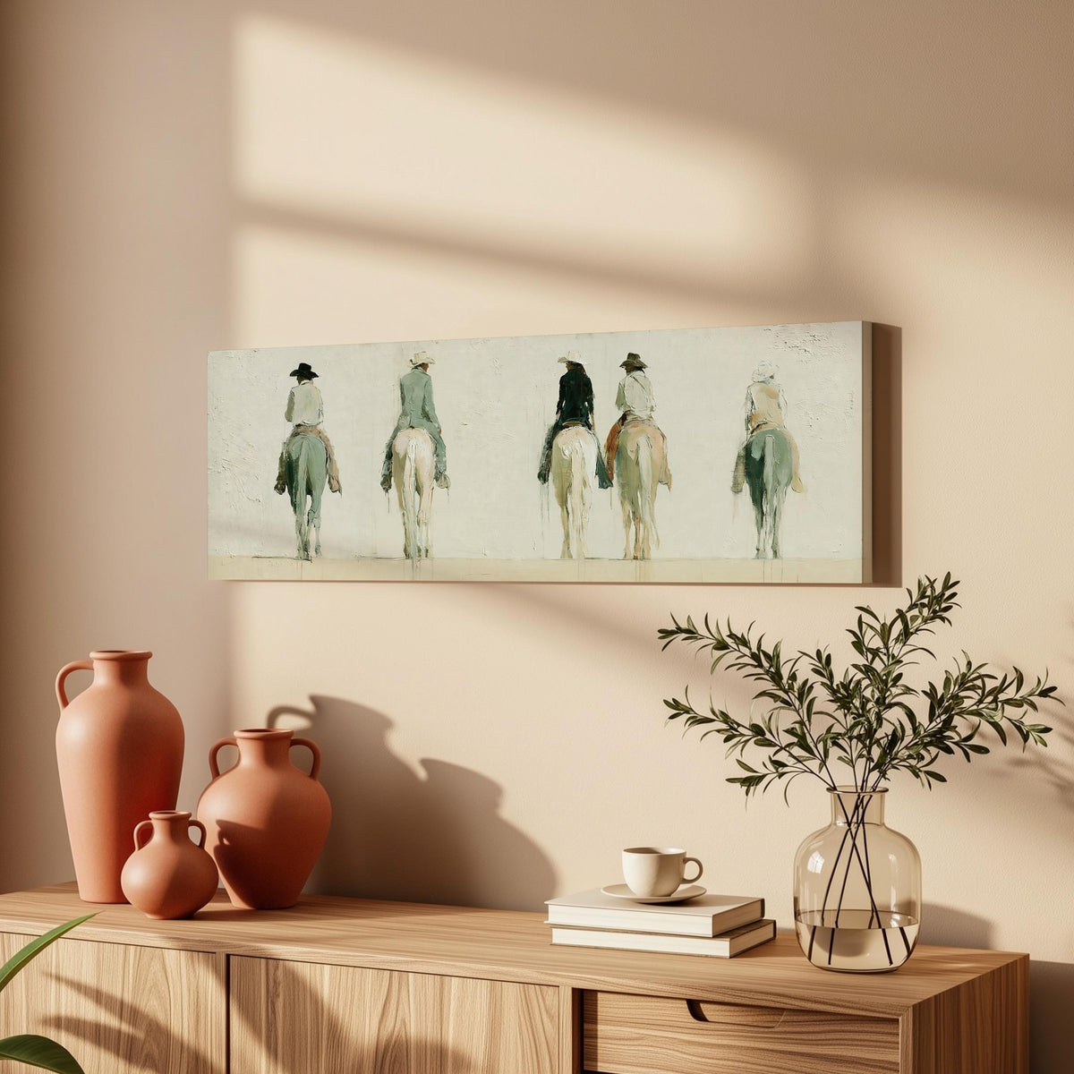 Riders on horseback seen from behind long horizontal canvas print above a wooden sideboard