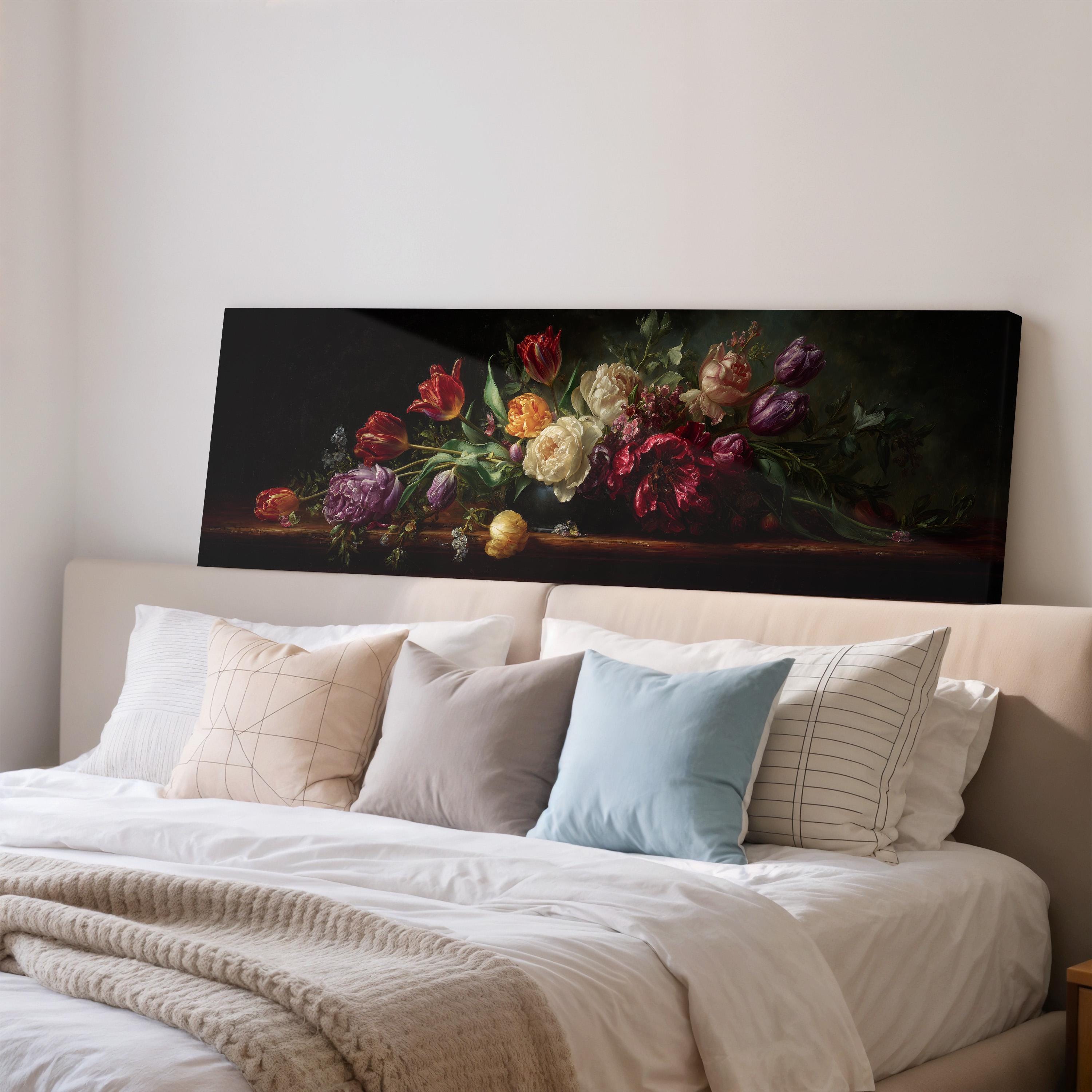 a large painting of a bouquet of flowers displayed on a wall above a bed with white bedding and pillows.