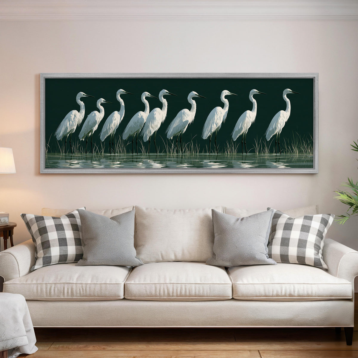 Row of white egrets on deep green panoramic canvas print above a white sofa in a bright living room