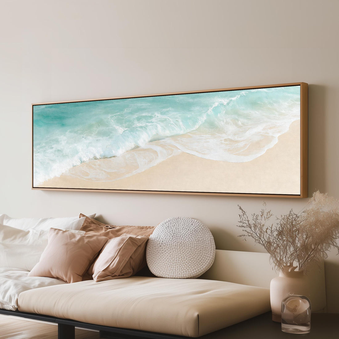 Turquoise wave washing onto sand from above long horizontal canvas print above a sofa in a living room