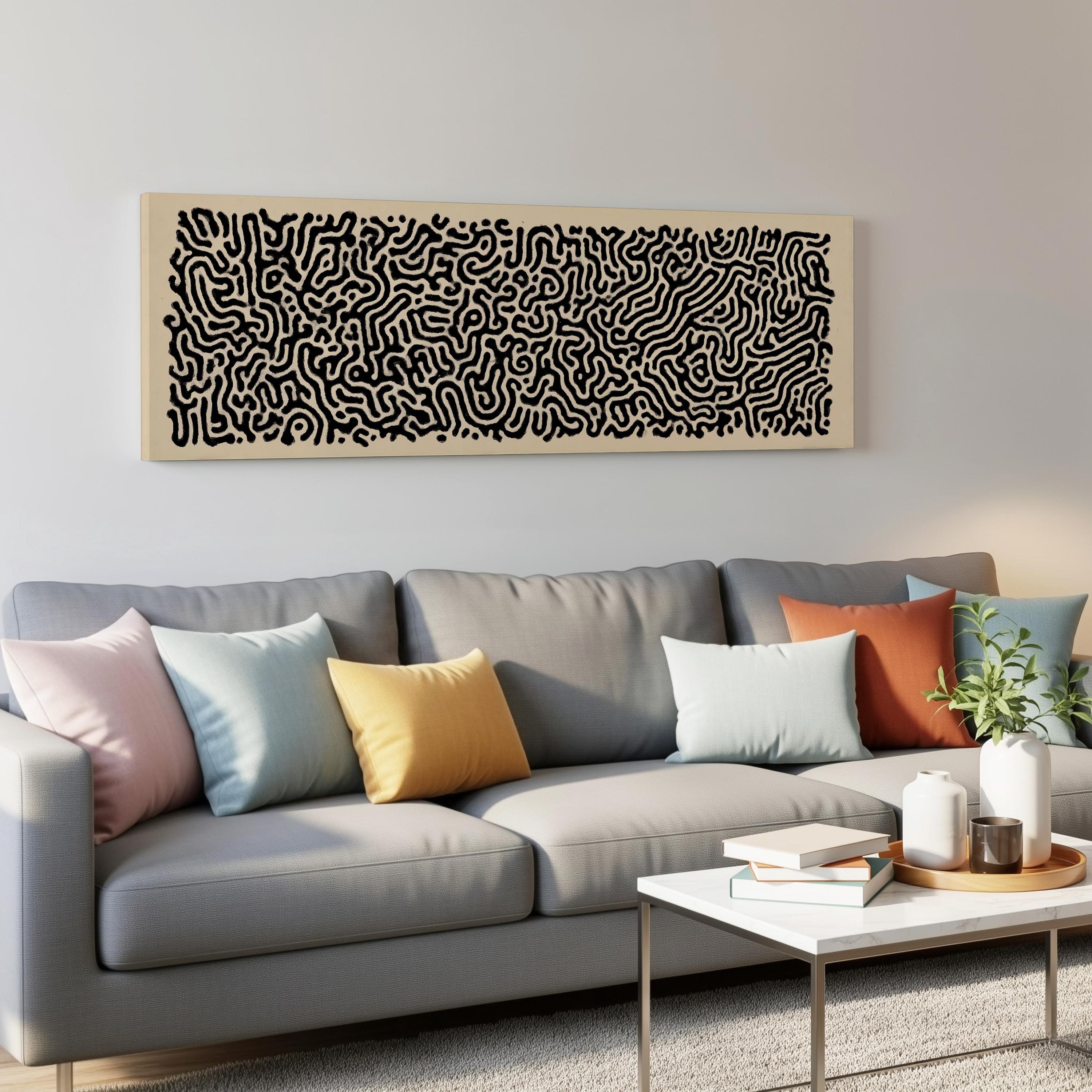 a modern living room with a gray sofa adorned with colorful throw pillows. Above the sofa, there is a large abstract art piece with a black and white pattern. On the coffee table, there are a few books and a small plant, creating a cozy and inviting atmosphere.