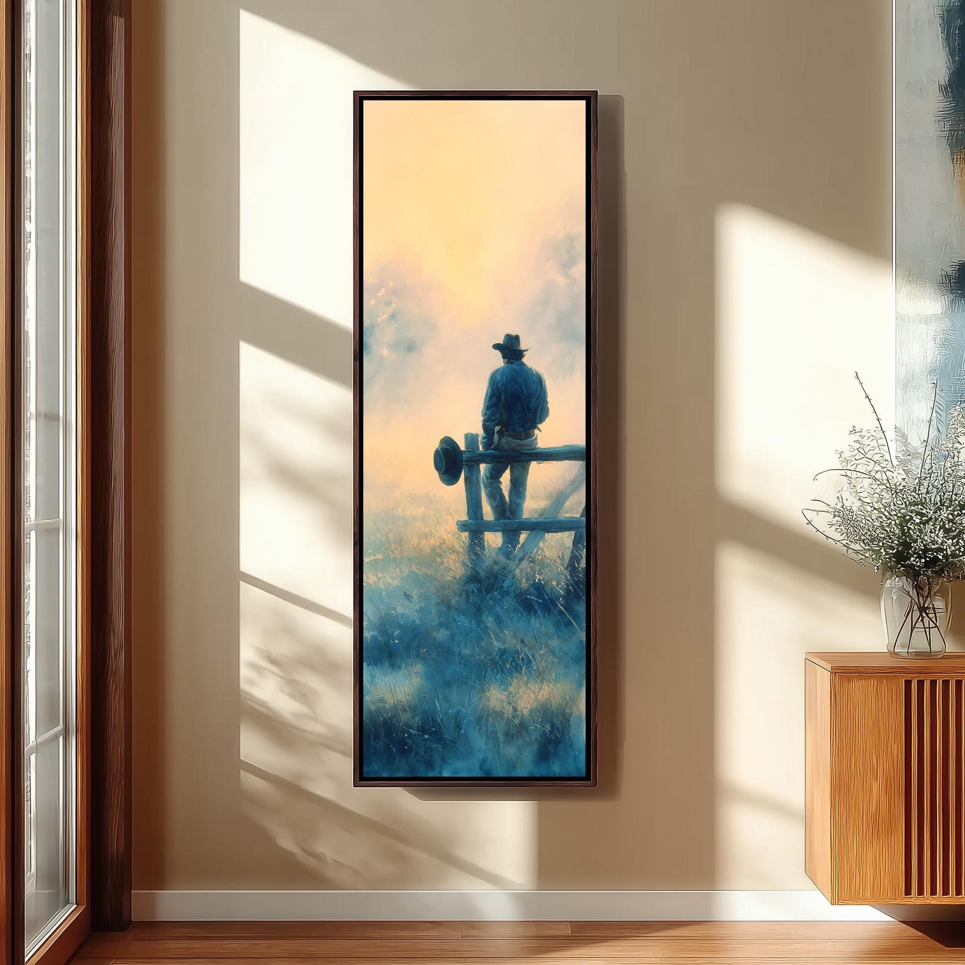 a large framed painting of a cowboy standing on a fence, with a serene landscape in the background.
