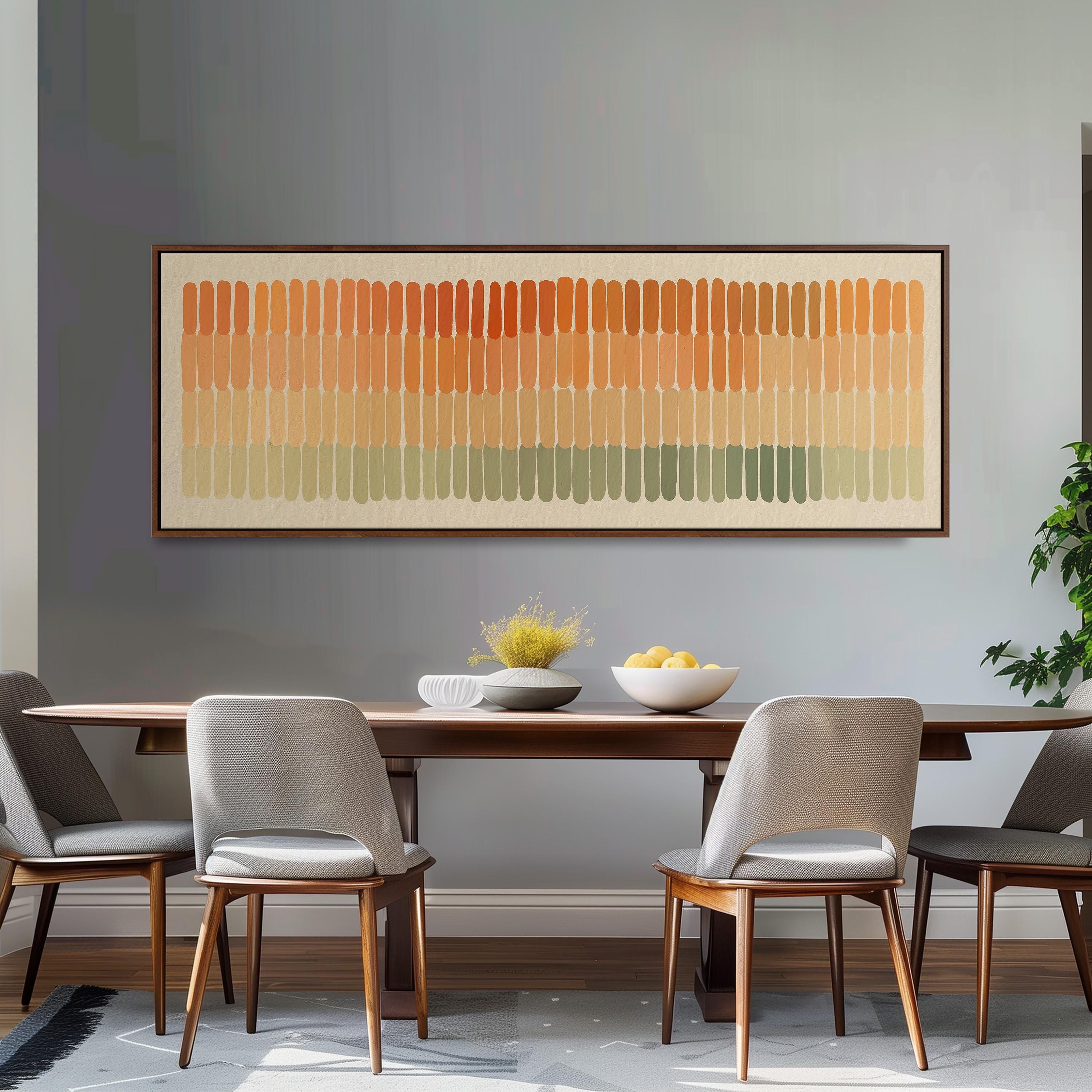 a dining room with a wooden table and four gray chairs. Above the table, there is a large abstract painting with horizontal stripes in various shades of orange, yellow, and green. The table is set with a bowl of fruit and a vase of flowers, creating a warm and inviting atmosphere.