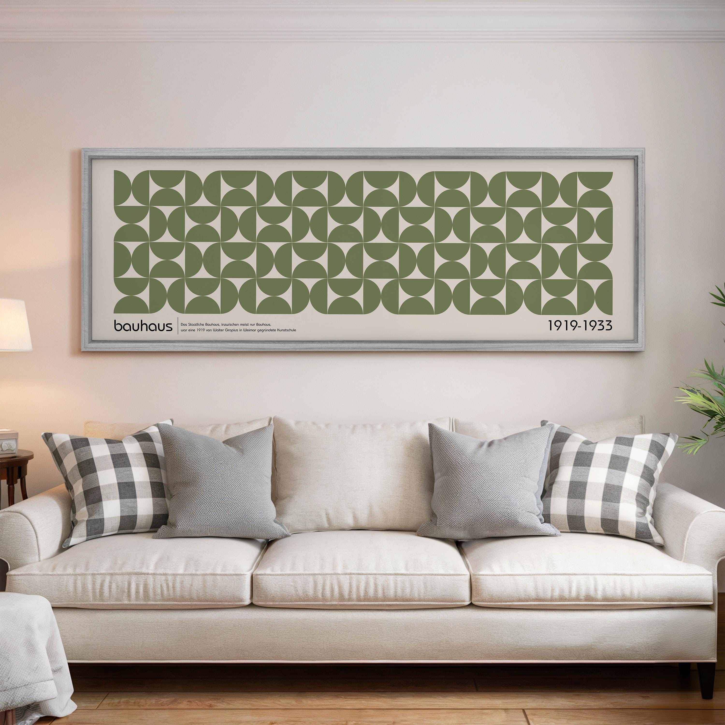 a living room with a white sofa and a large framed poster of a repeating geometric pattern above it.