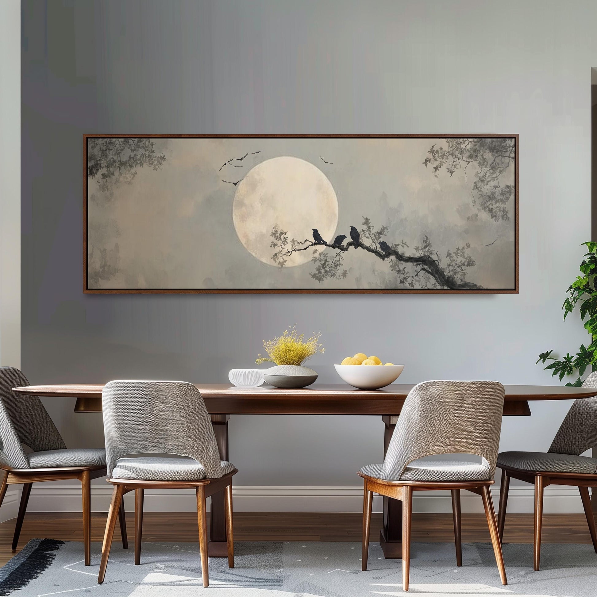 a dining room with a large painting of a moonlit night scene hanging on the wall above a wooden dining table with four chairs. The table is set with a bowl of fruit and a vase of flowers, creating a cozy and inviting atmosphere.