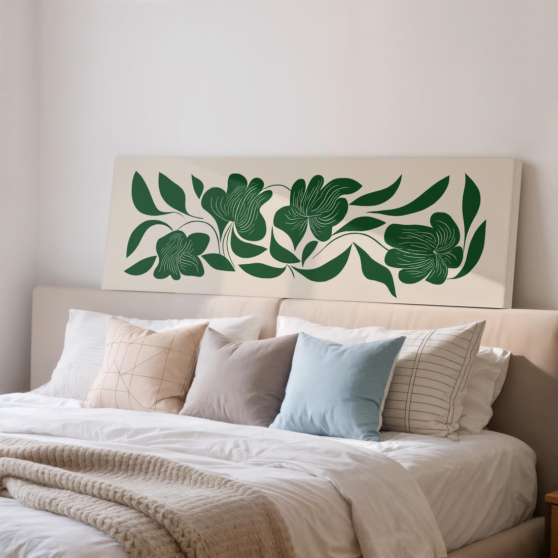a large, framed artwork of green leaves and flowers hanging on a wall above a brown sofa.