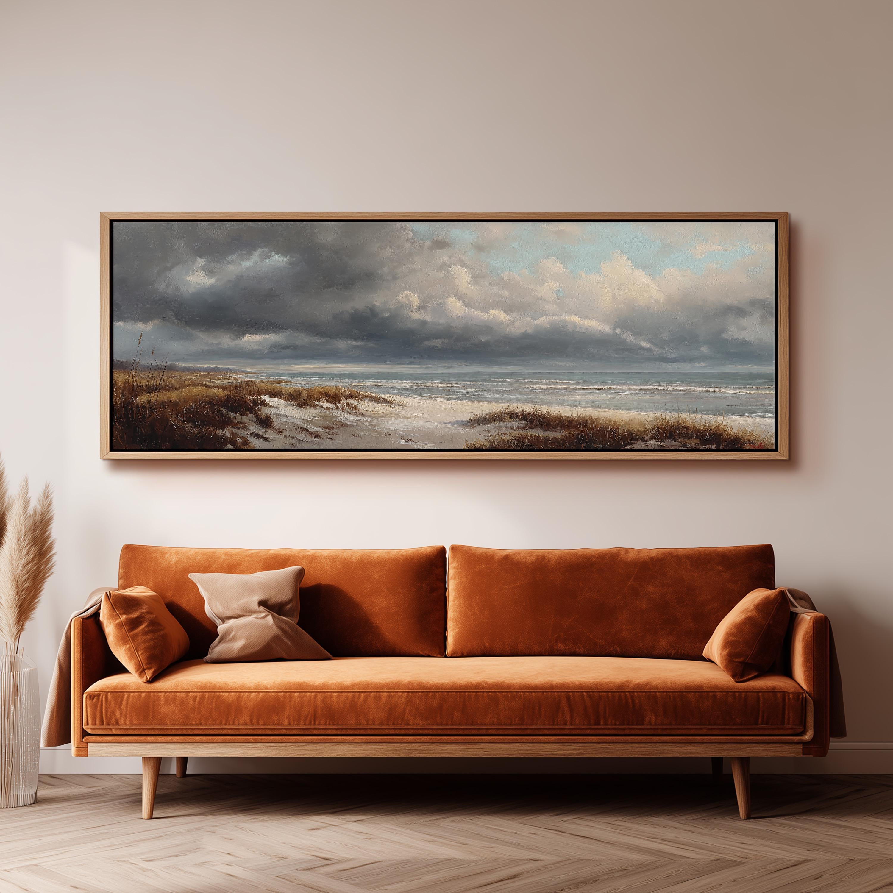 a large, framed painting of a beach scene hanging on a wall above a brown sofa.