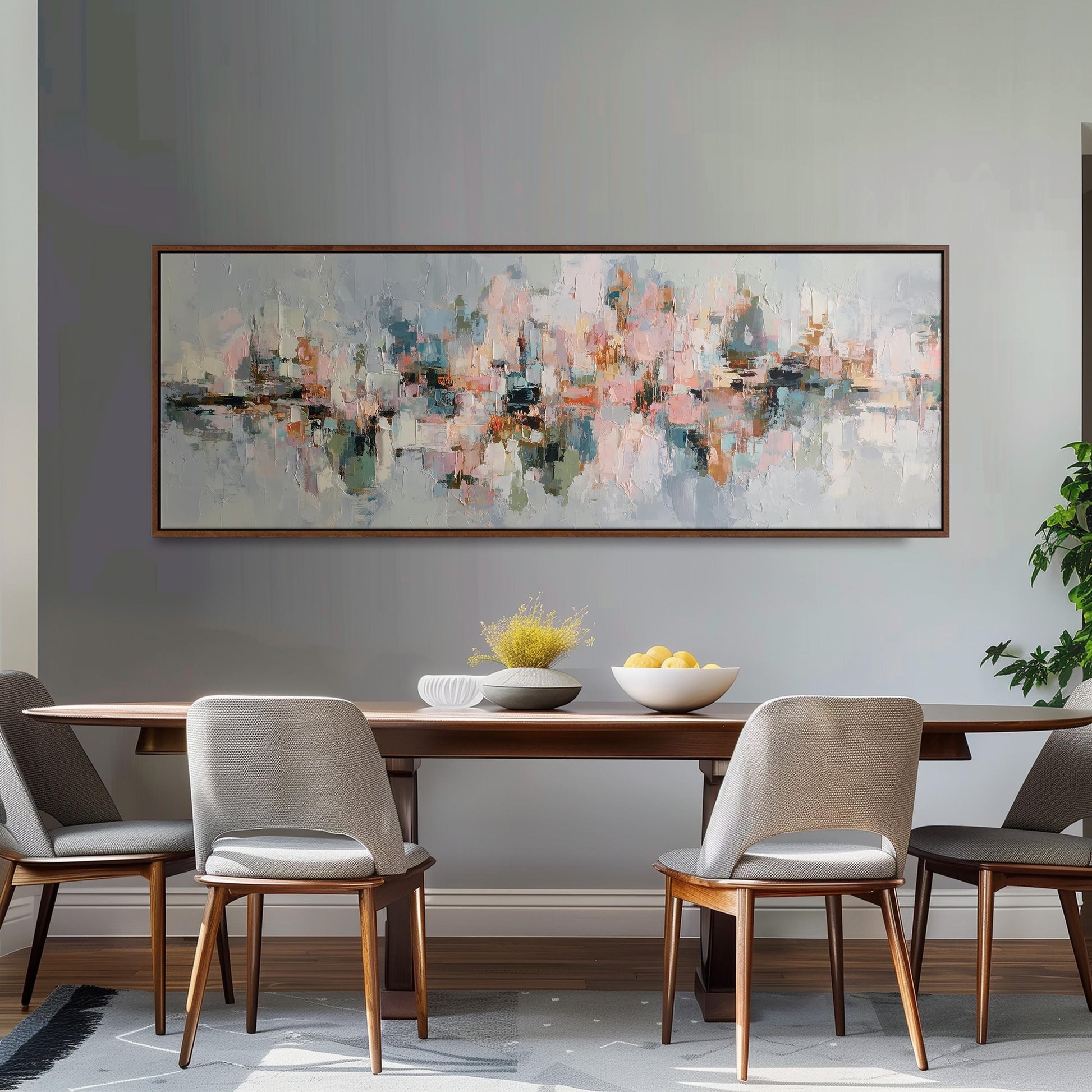 a dining room with a large abstract painting hanging on the wall above a wooden dining table with four chairs. The table is set with a bowl of fruit and a vase of flowers, creating a cozy and inviting atmosphere.