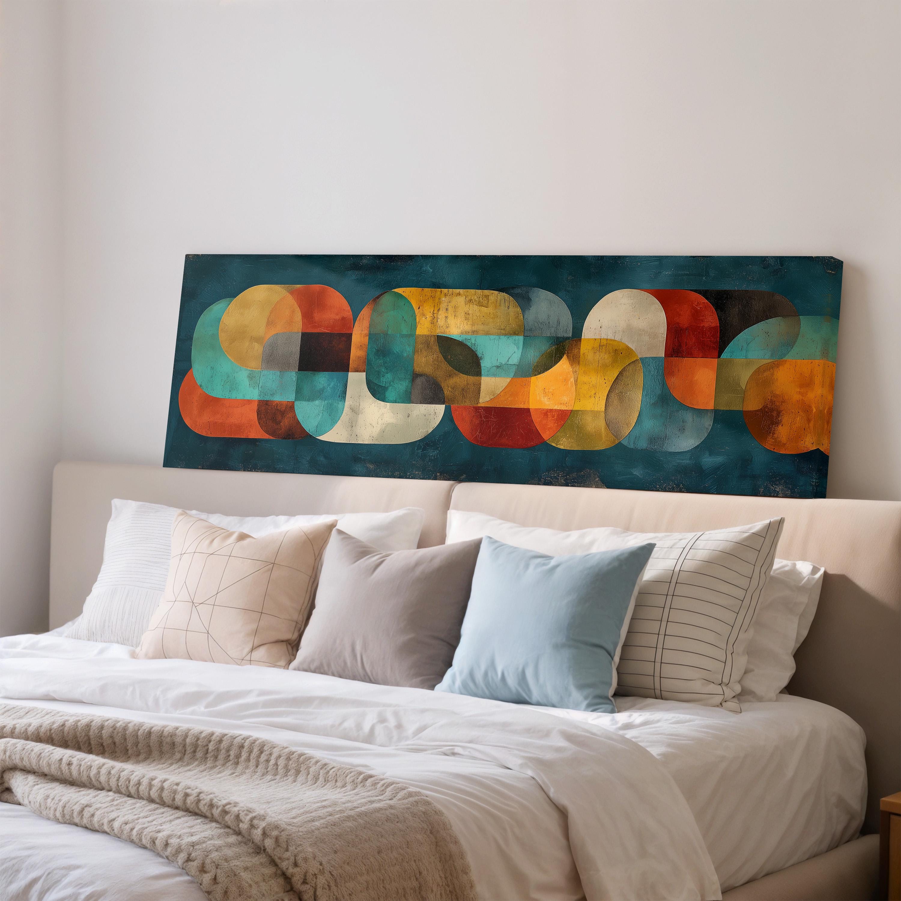 a large abstract painting hanging on a wall above a bed with white pillows and a gray blanket.