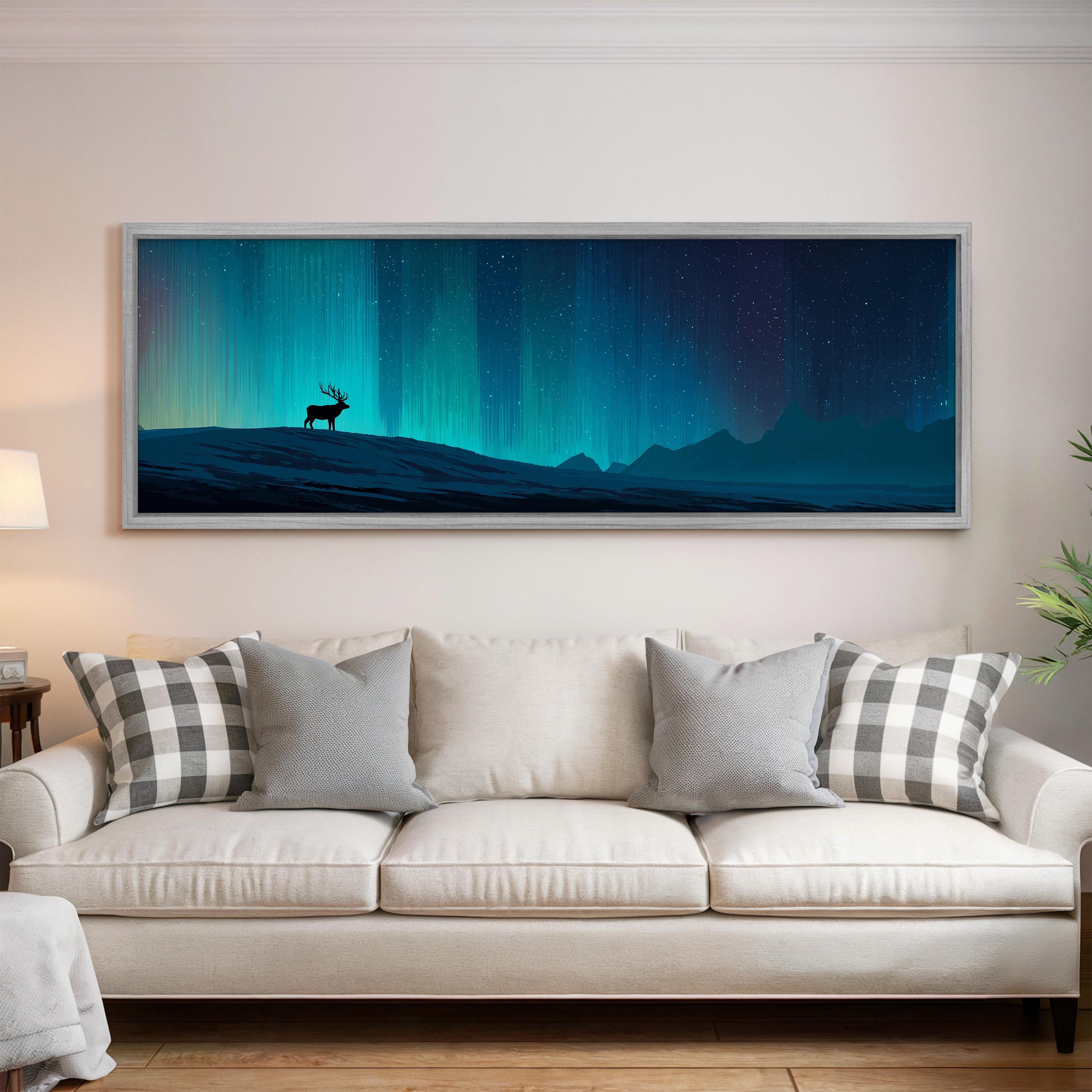 a large, framed painting of a deer standing on a hill against a night sky with a stunning display of the northern lights.