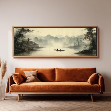 a large, framed painting of a serene landscape with a boat on a lake, hanging on a wall above a brown sofa.