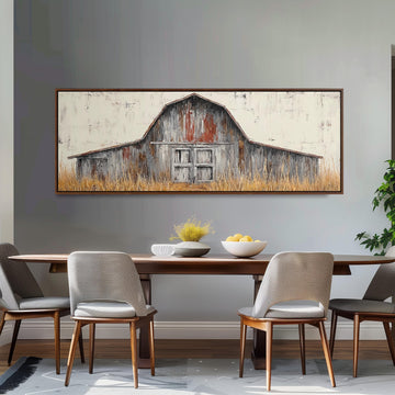 a dining room with a large painting of a barn hanging on the wall above a wooden table with four chairs. The painting depicts a rustic barn with a weathered wooden exterior and a large door. The dining table is set with a bowl of fruit and a vase of flowers, creating a cozy and inviting atmosphere.