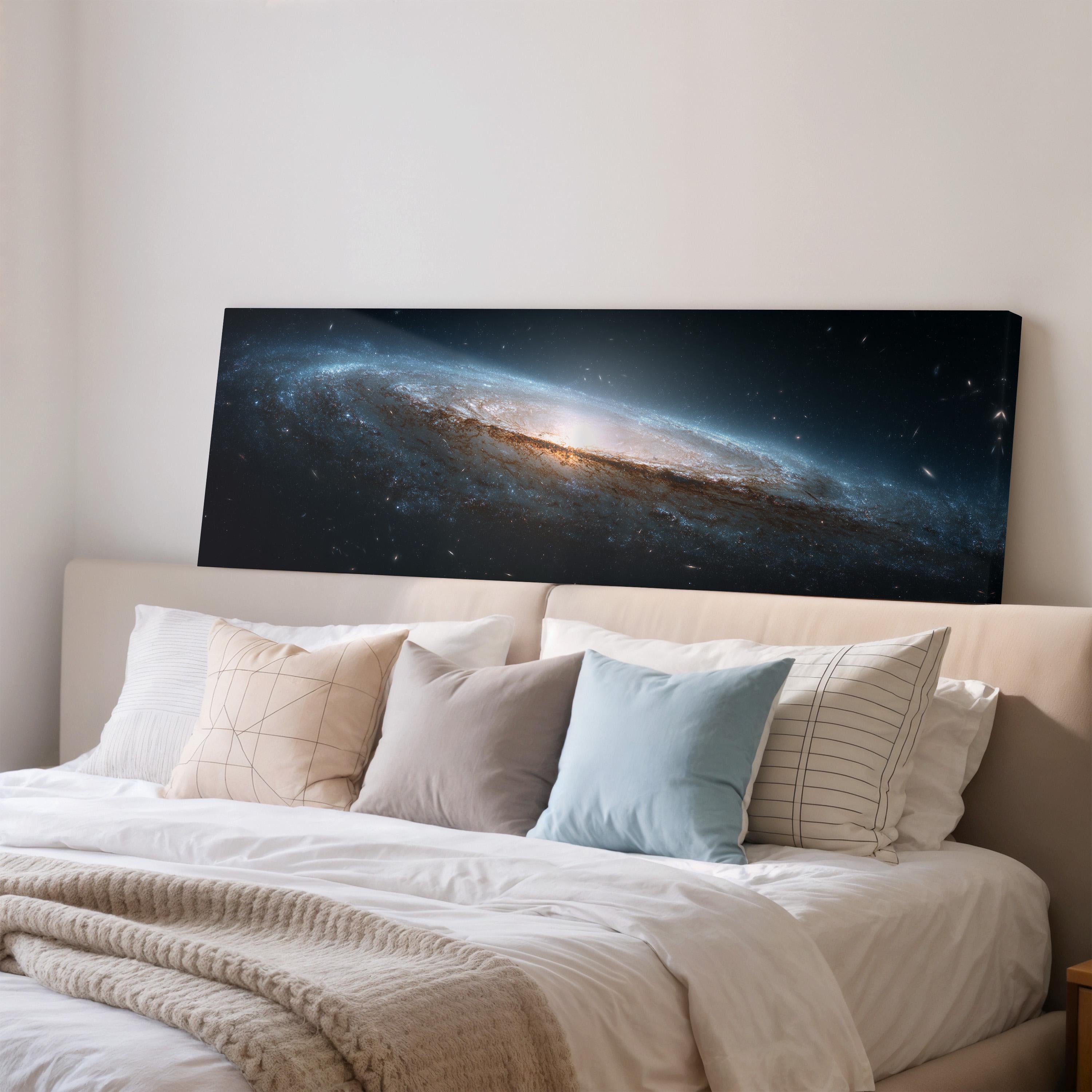 a large, black canvas print of a galaxy hanging on a wall above a bed with white bedding and pillows.