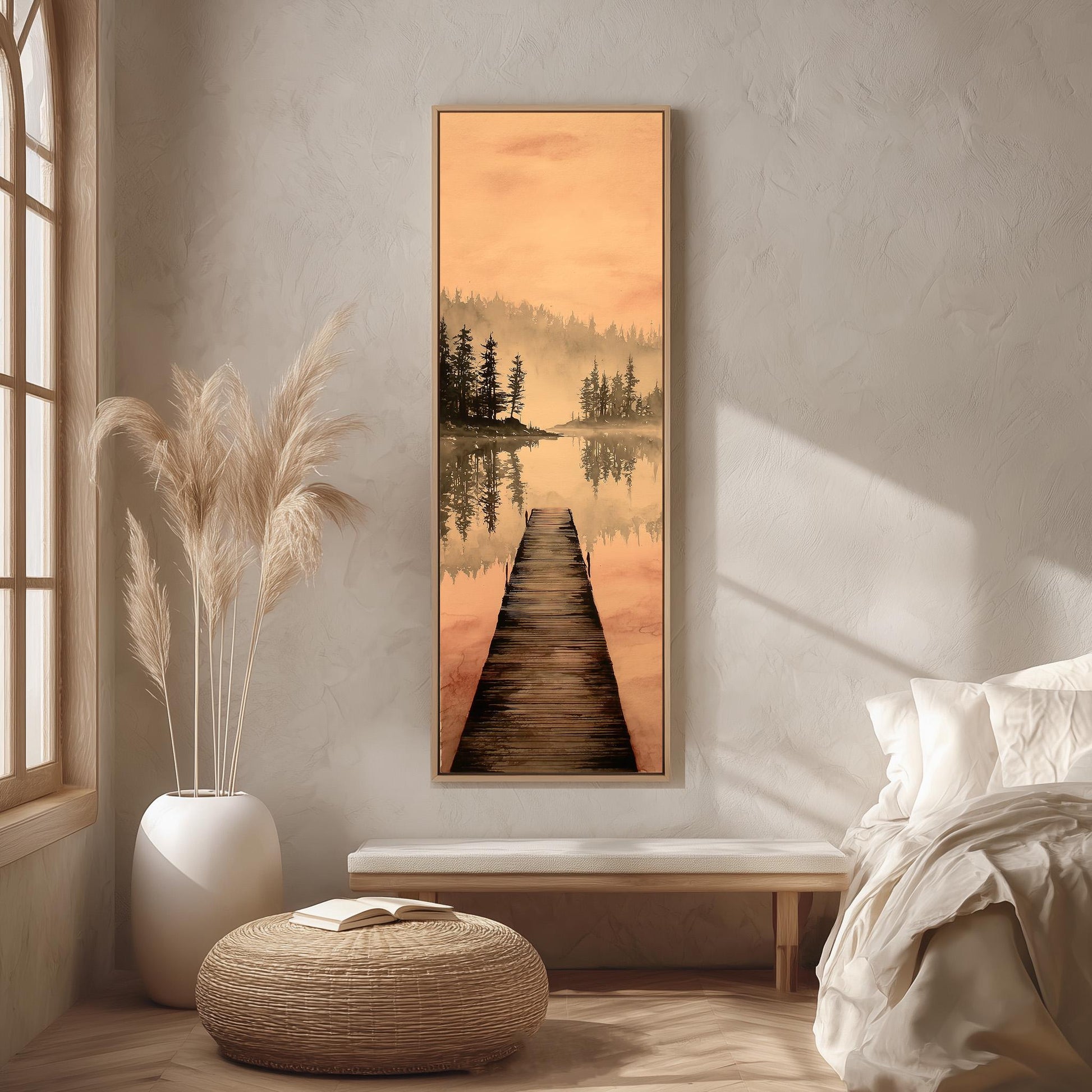 a serene bedroom scene with a large painting of a wooden dock leading to a lake, surrounded by trees and a warm orange sky. The painting is hung on the wall above a bed with white bedding, and a wicker ottoman is placed in front of the bed. The room has a minimalist and calming aesthetic, with natural elements like the potted plant and the painting adding to the overall ambiance.