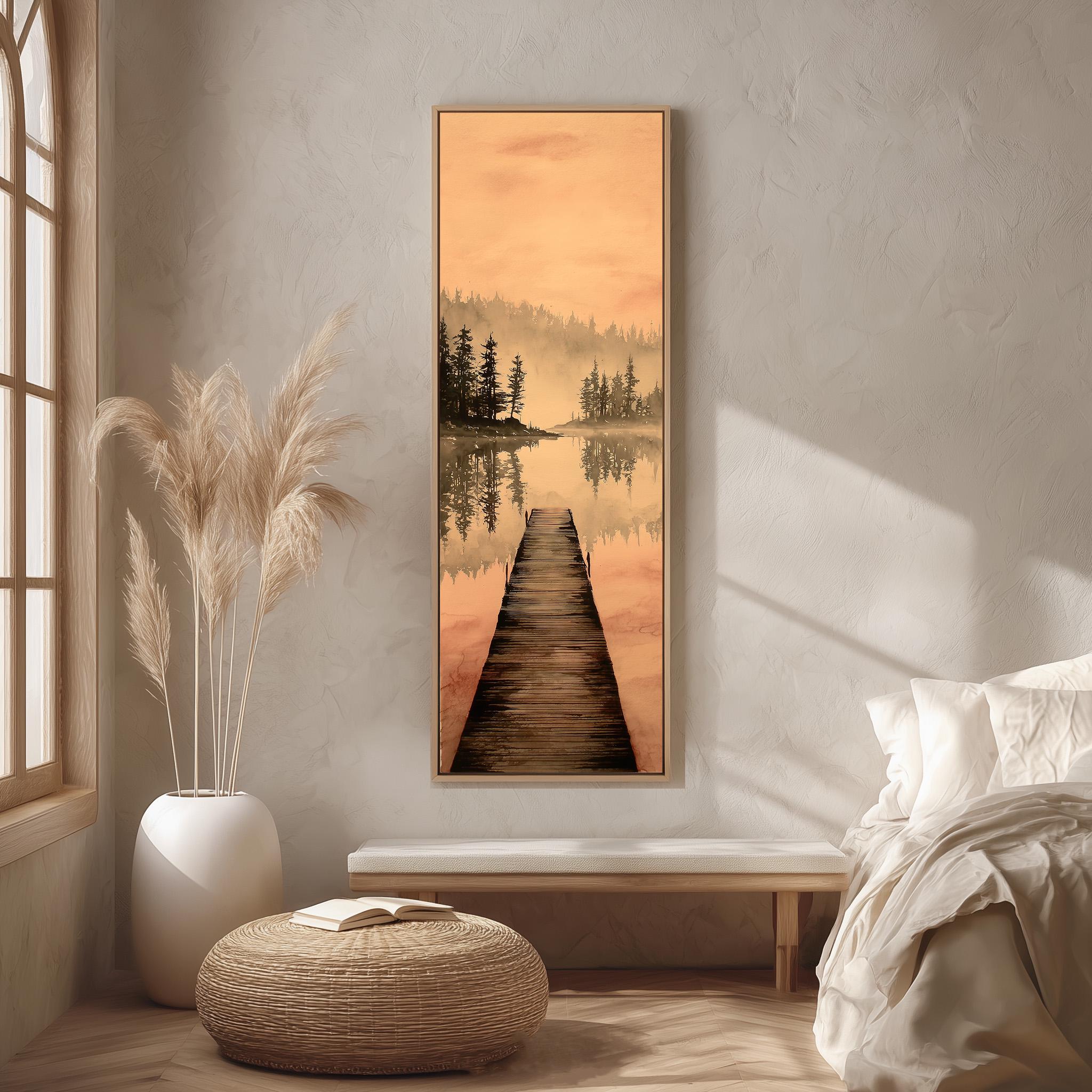 a serene bedroom scene with a large painting of a wooden dock leading to a lake, surrounded by trees and a warm orange sky. The painting is hung on the wall above a bed with white bedding, and a wicker ottoman is placed in front of the bed. The room has a minimalist and calming aesthetic, with natural elements like the potted plant and the painting adding to the overall ambiance.