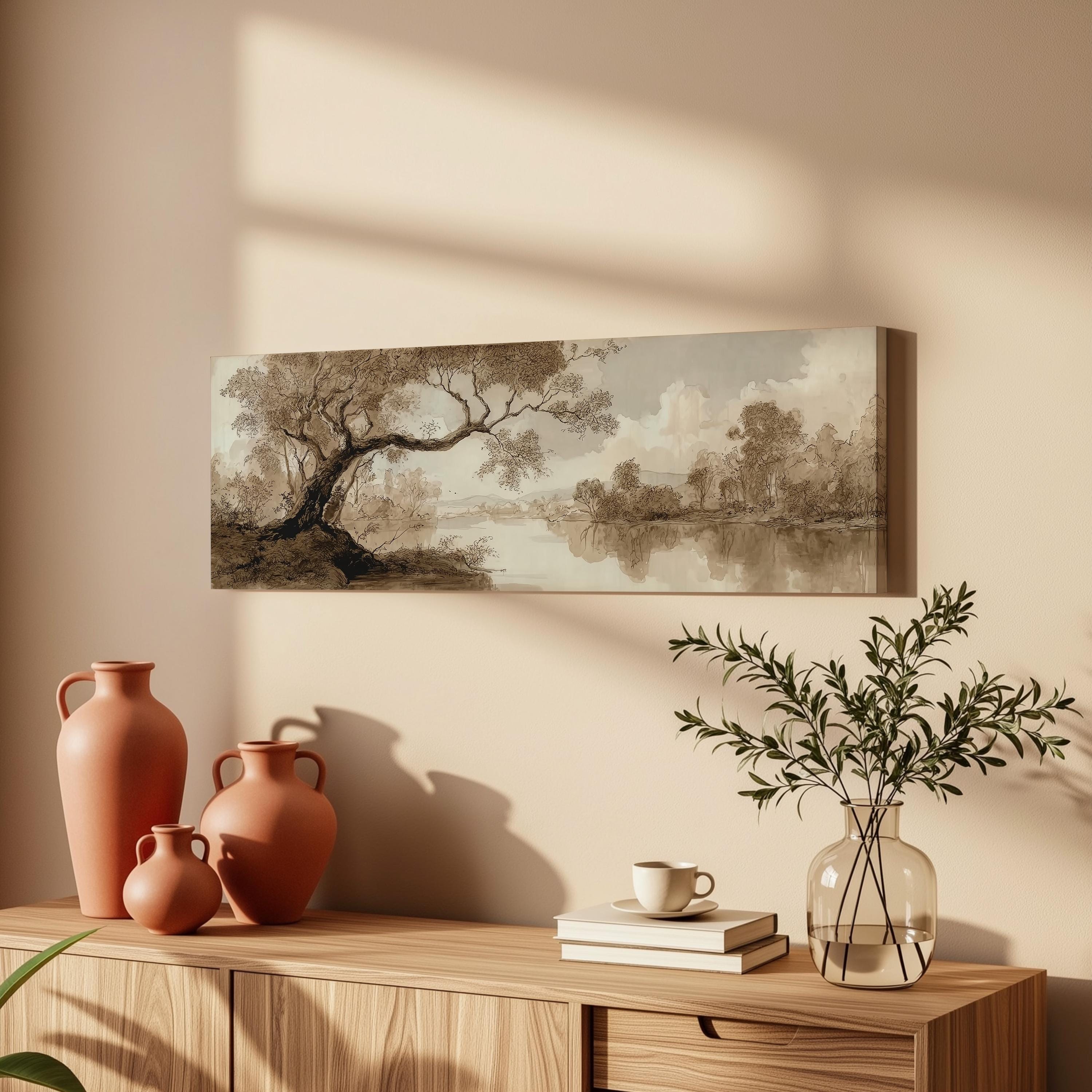 a wooden cabinet with a painting of a landscape hanging on the wall above it. The cabinet also has three orange vases and a glass vase with greenery, as well as a stack of books and a cup on the surface.