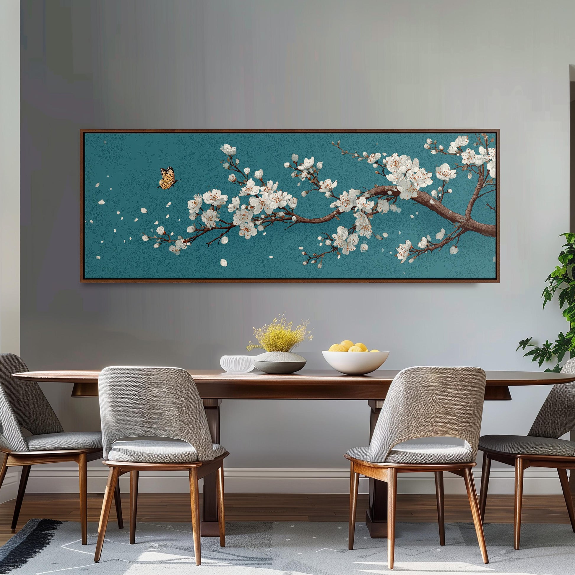 a dining room with a large framed painting of a cherry blossom tree on the wall above a wooden dining table with four chairs. The table is set with a bowl of fruit and a vase of flowers, creating a cozy and inviting atmosphere.