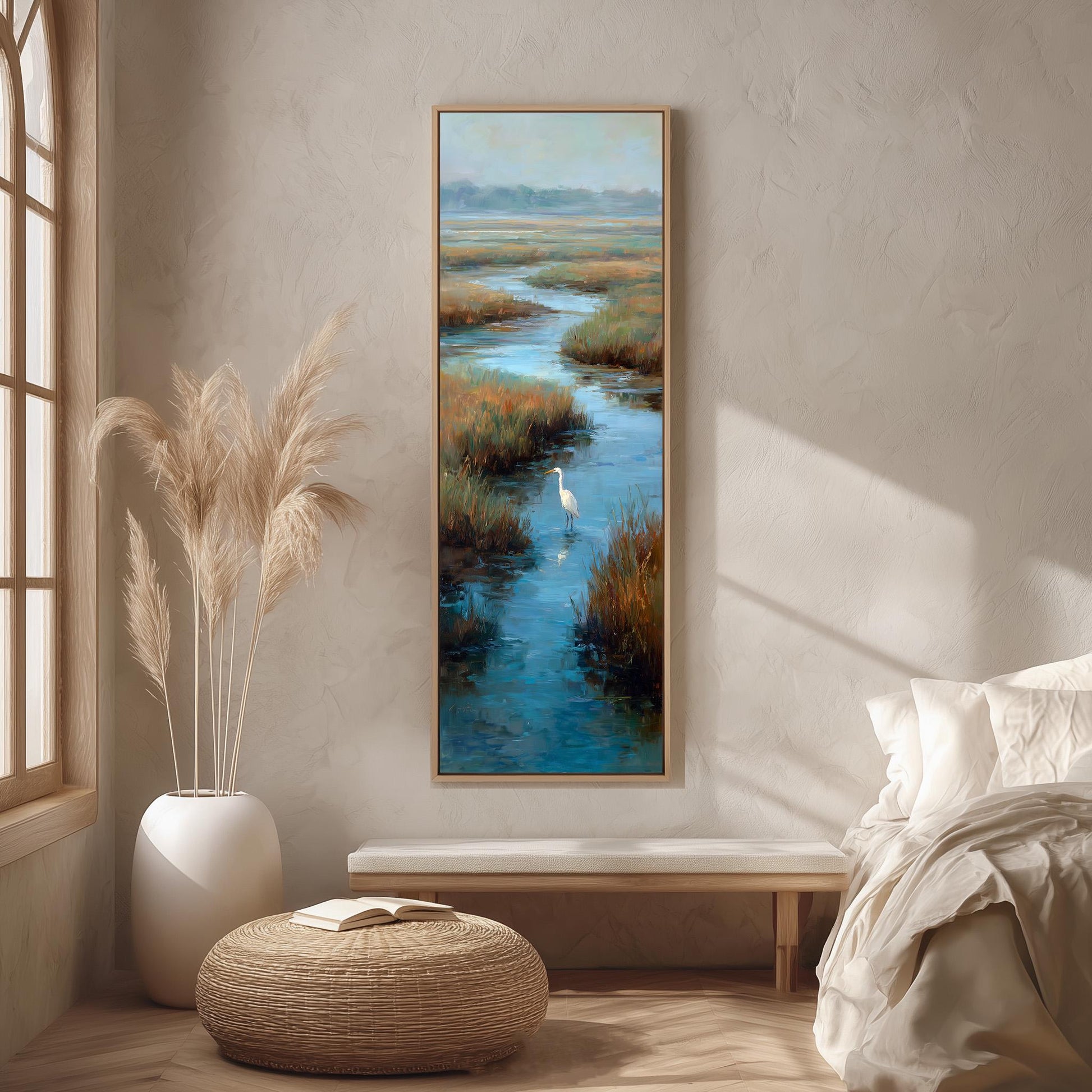 a serene bedroom scene with a large painting of a tranquil body of water and a bird in flight hanging on the wall. The painting is framed in a wooden frame and is the focal point of the room. The room is decorated with a white bed, a wicker ottoman, and a potted plant, creating a calm and peaceful atmosphere.