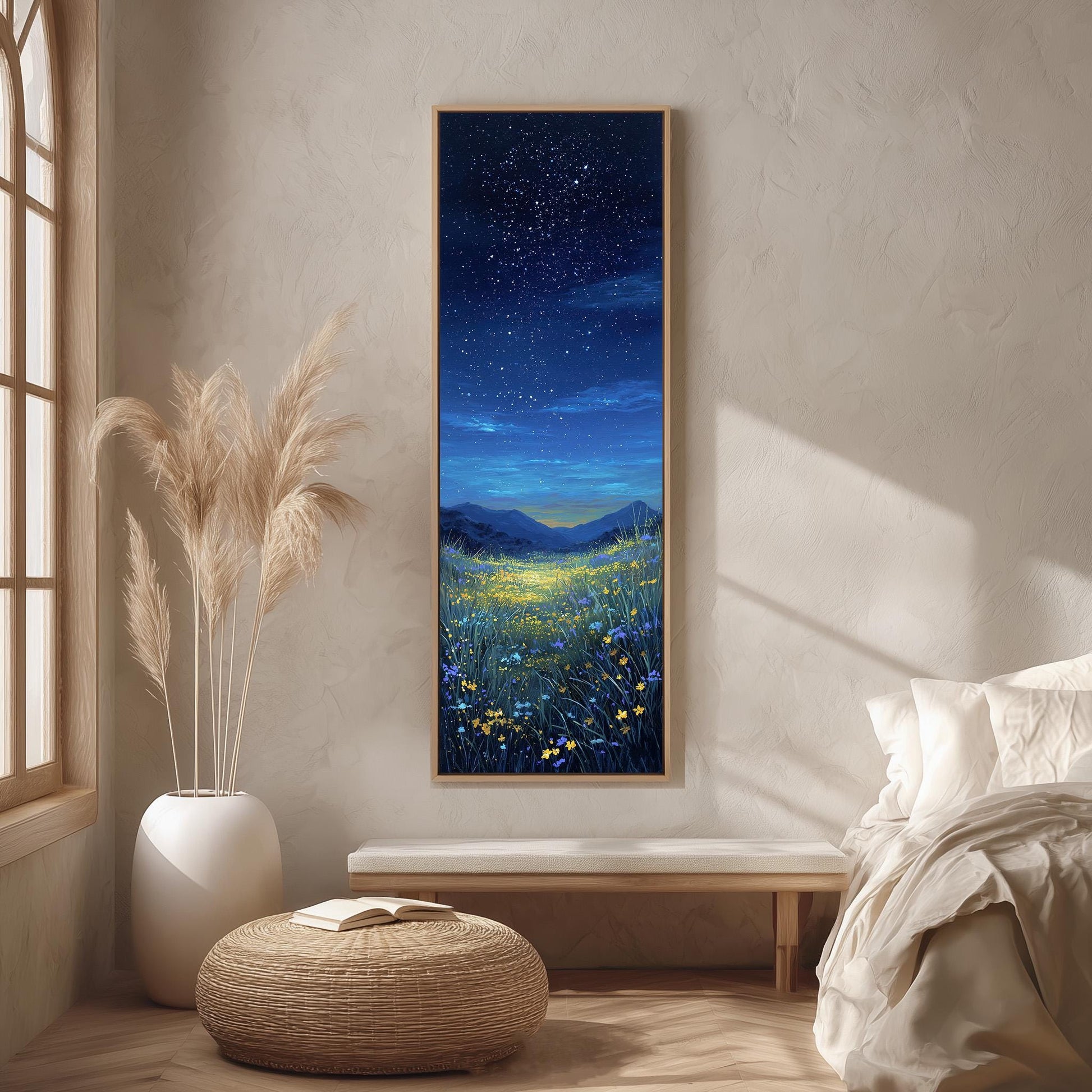 a serene bedroom scene with a large painting of a starry night sky above a field of flowers hanging on the wall. The painting is framed in a wooden frame and is the focal point of the room. The room features a bed with white linens, a wicker ottoman, and a potted plant, creating a cozy and inviting atmosphere.