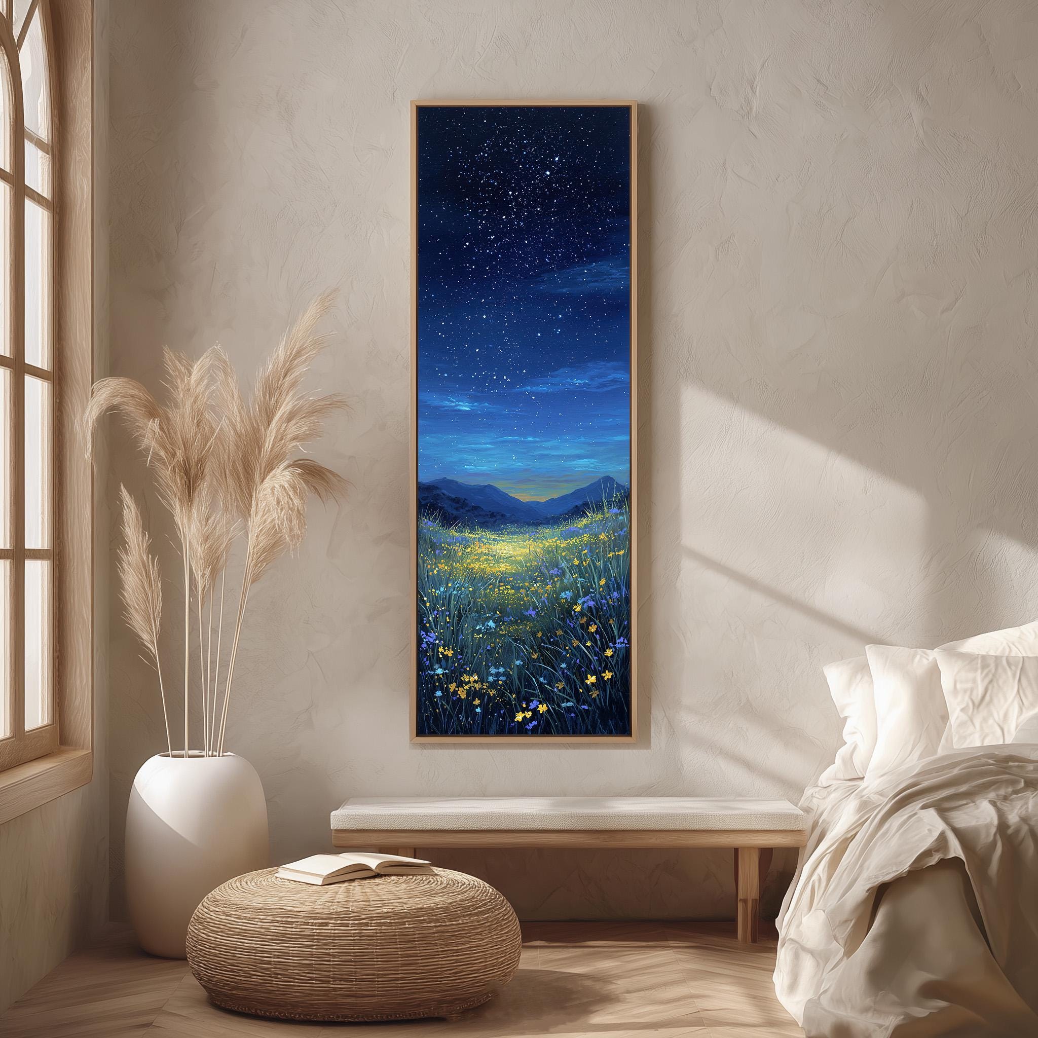 a serene bedroom scene with a large painting of a starry night sky above a field of flowers hanging on the wall. The painting is framed in a wooden frame and is the focal point of the room. The room features a bed with white linens, a wicker ottoman, and a potted plant, creating a cozy and inviting atmosphere.
