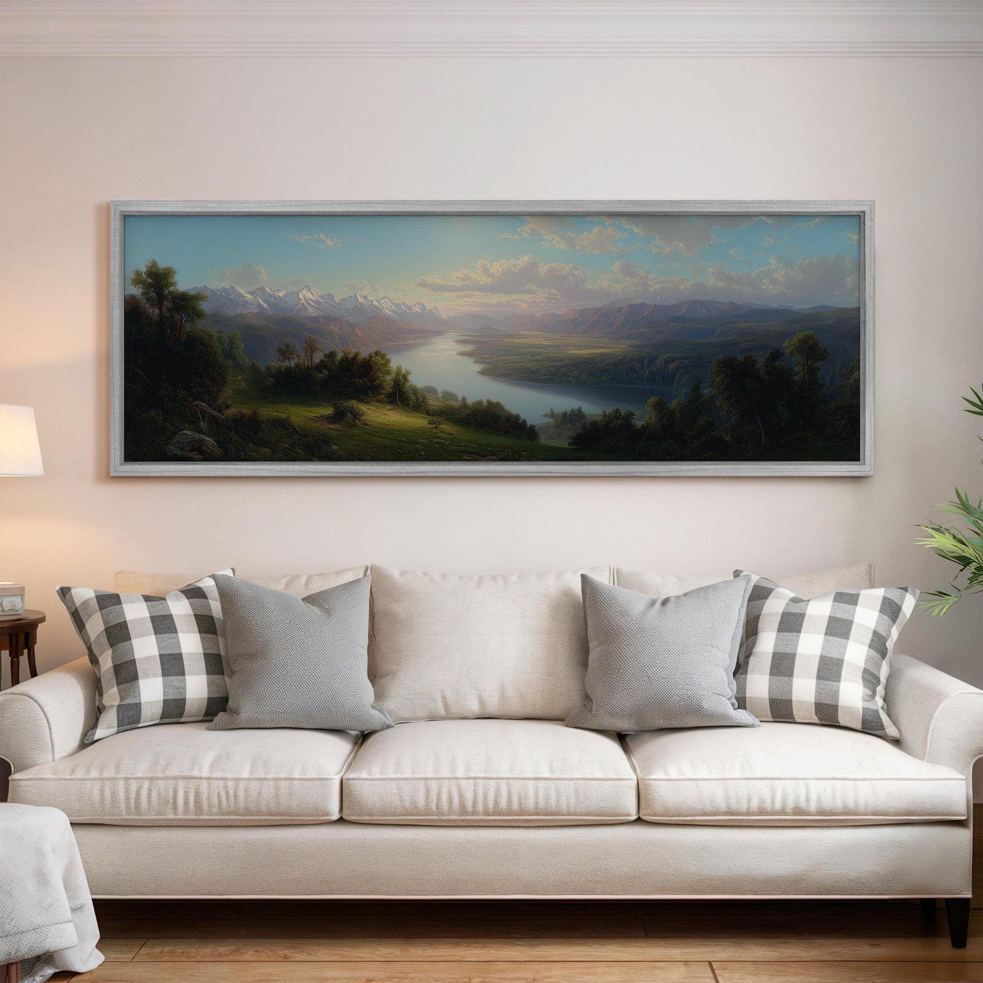 a large landscape painting hanging on a wall above a white sofa with gray and white patterned pillows.