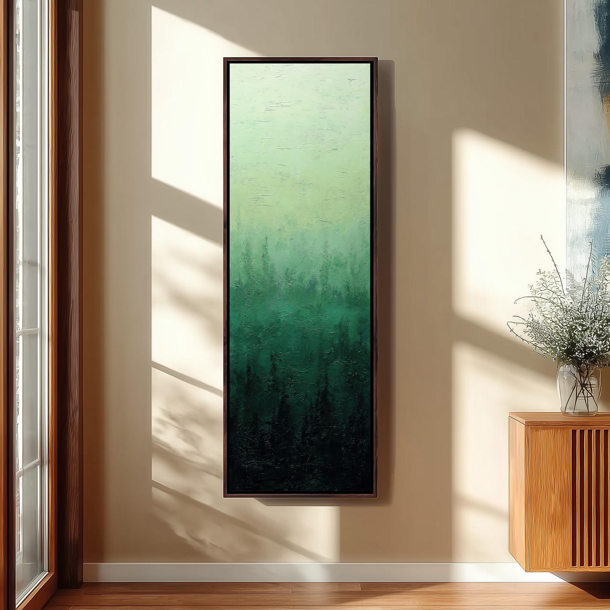 a large, framed painting of a forest scene hanging on a wall in a room with a wooden floor and a window.
