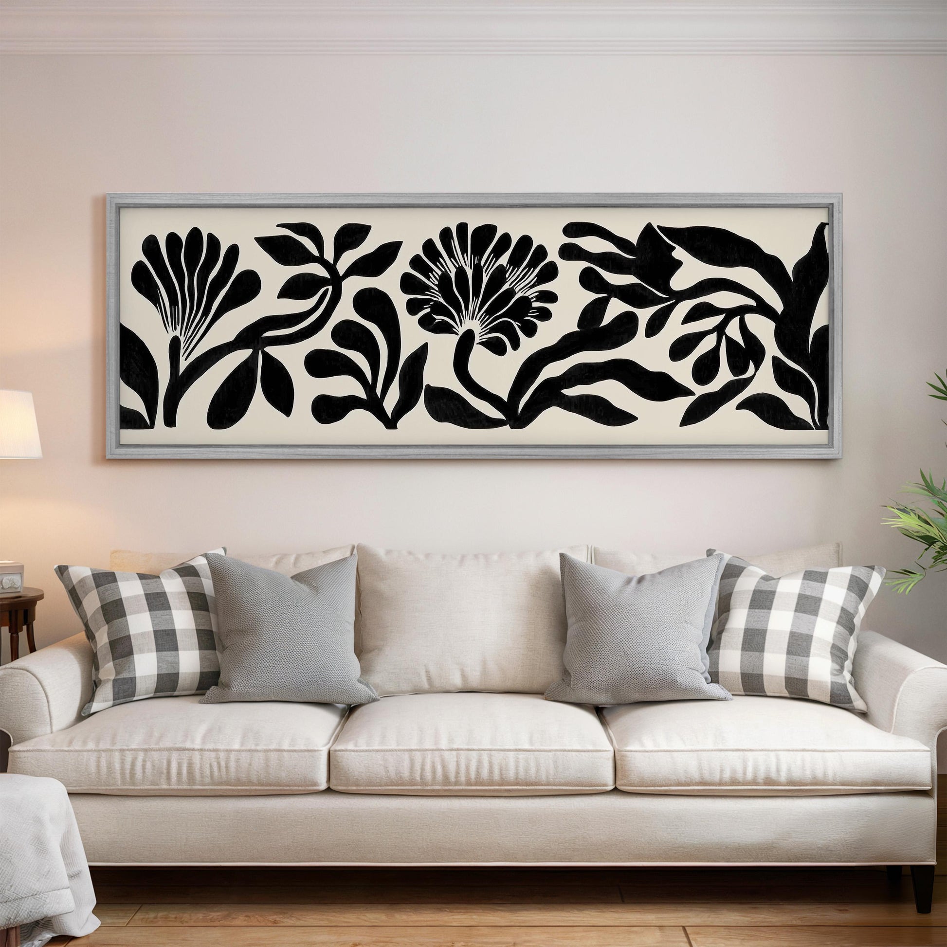 a large black and white floral print hanging on a wall above a white sofa with gray and white patterned throw pillows.