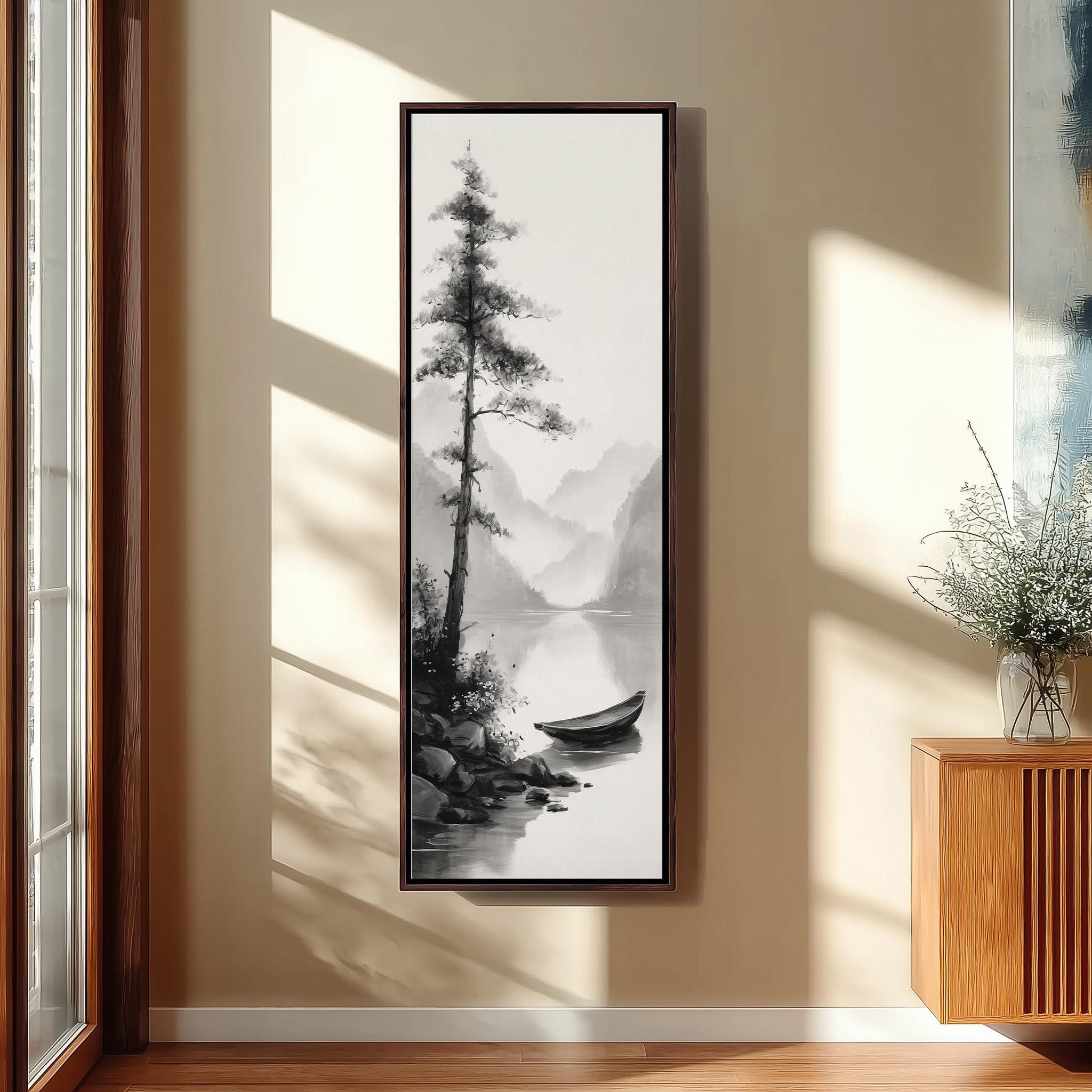 a large black and white painting of a boat on a lake, hanging on a wall in a room with a wooden cabinet and a vase of flowers.