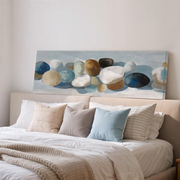 a large painting of rocks on a wall above a bed with white pillows and a gray blanket.