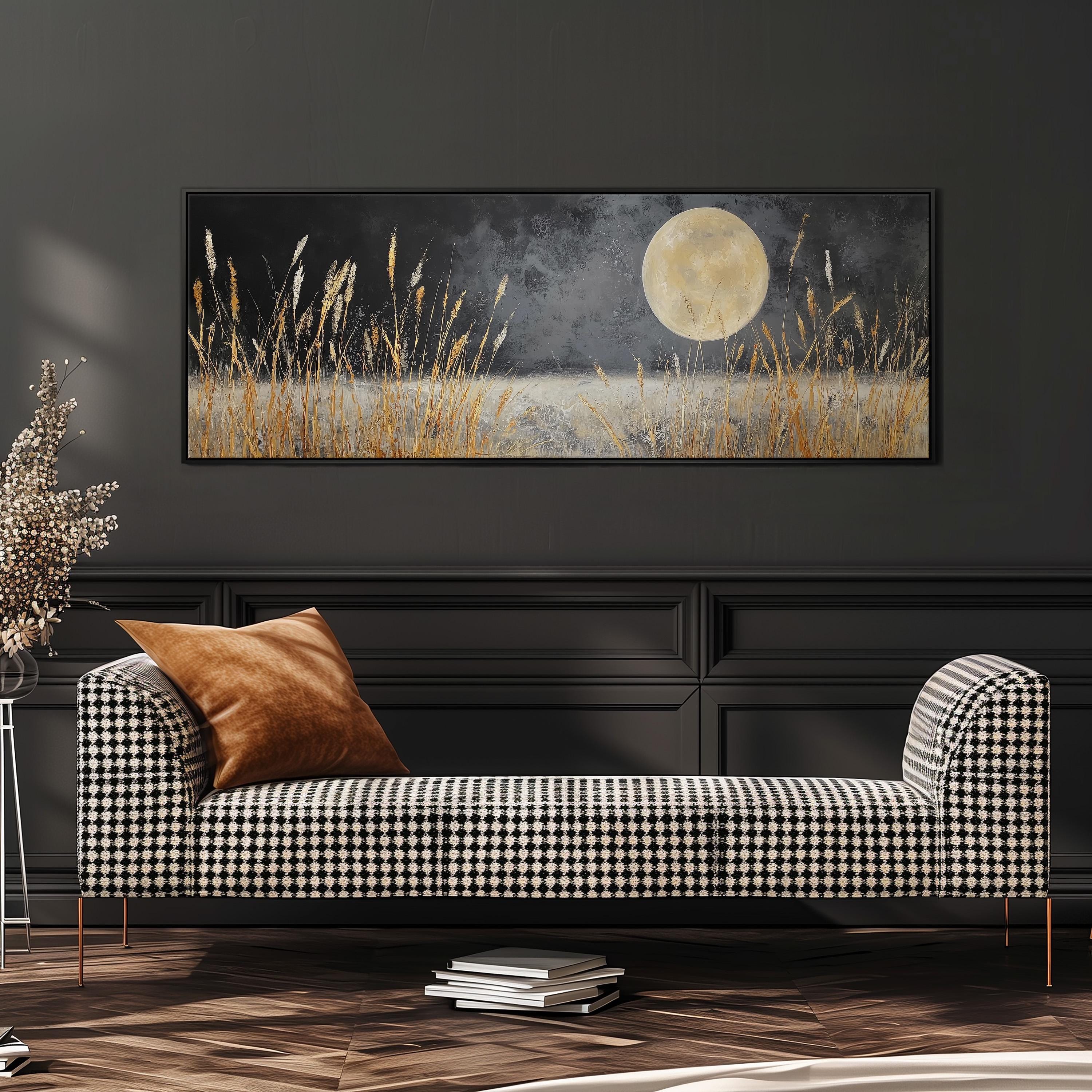 a large black and white checkered sofa with a brown throw pillow, set against a dark wall with a framed painting of a field with tall grass and a full moon in the background.