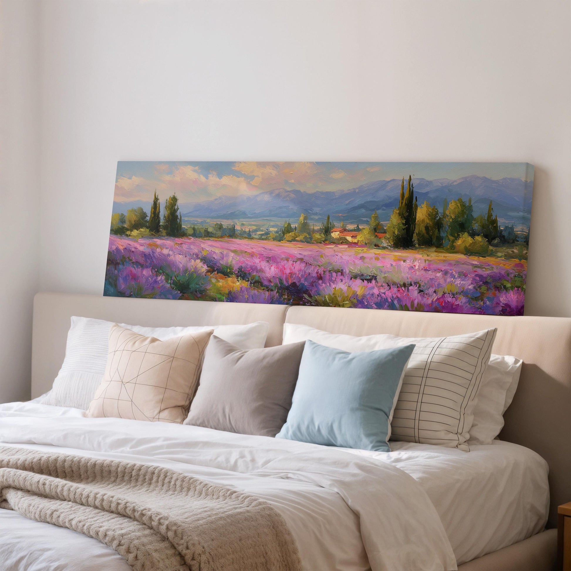 a large painting of a field of flowers hanging on a wall above a bed with white pillows and a gray blanket.