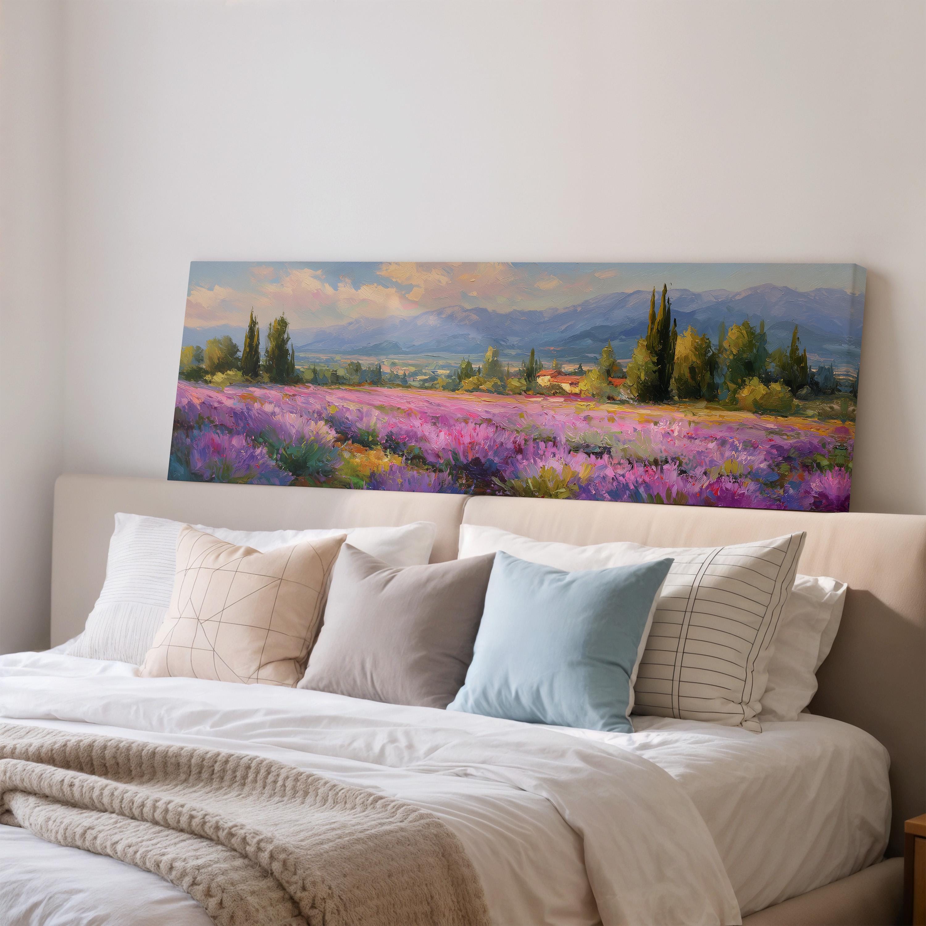 a large painting of a field of flowers hanging on a wall above a bed with white pillows and a gray blanket.