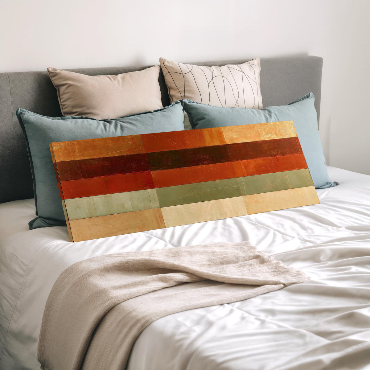 Amber, rust and sage horizontal color bands wide panoramic canvas print laid on a bed to show its size